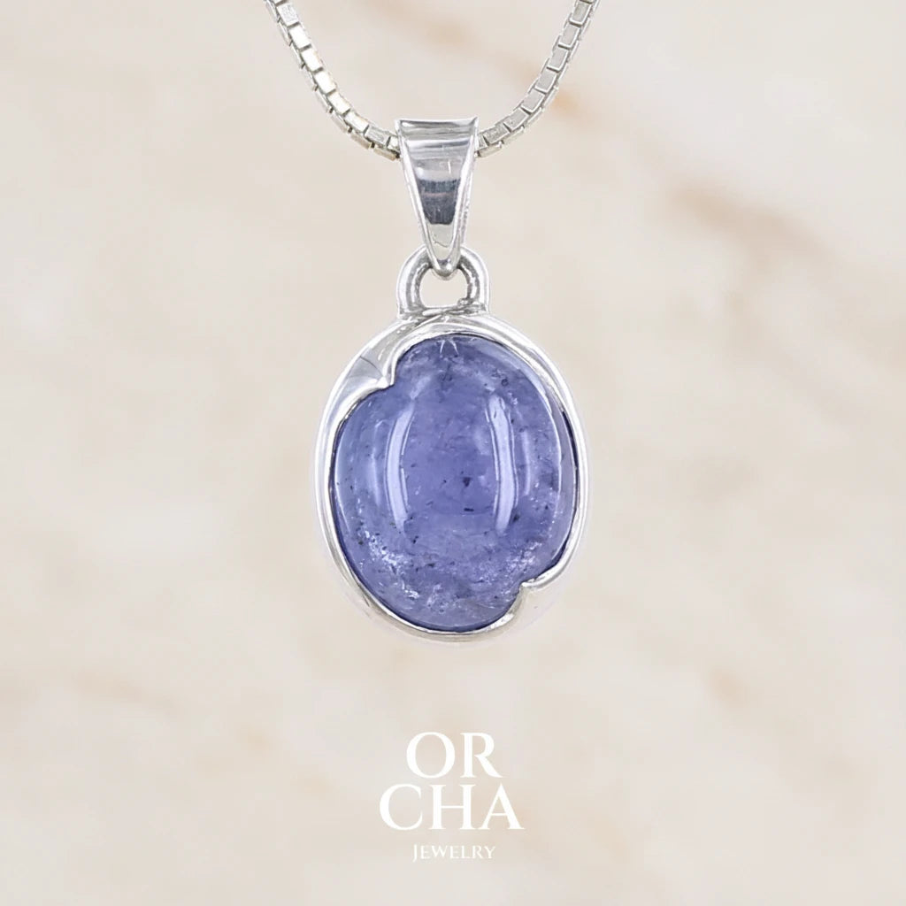 pendentif pour femme en argent massif serti d'un cabochon de Tanzanite de couleur bleu lavande . Pierre translucide présentant des inclusions. Pierre ayant subit un traitement de chauffe, traitement admis et fréquent en gemmologie pour ce type de pierre . Bijoux unique, éthique et durable présenté dans un coffret de notre marque, prêt à offrir. Livraison offerte, certificat d'authenticité, service client.