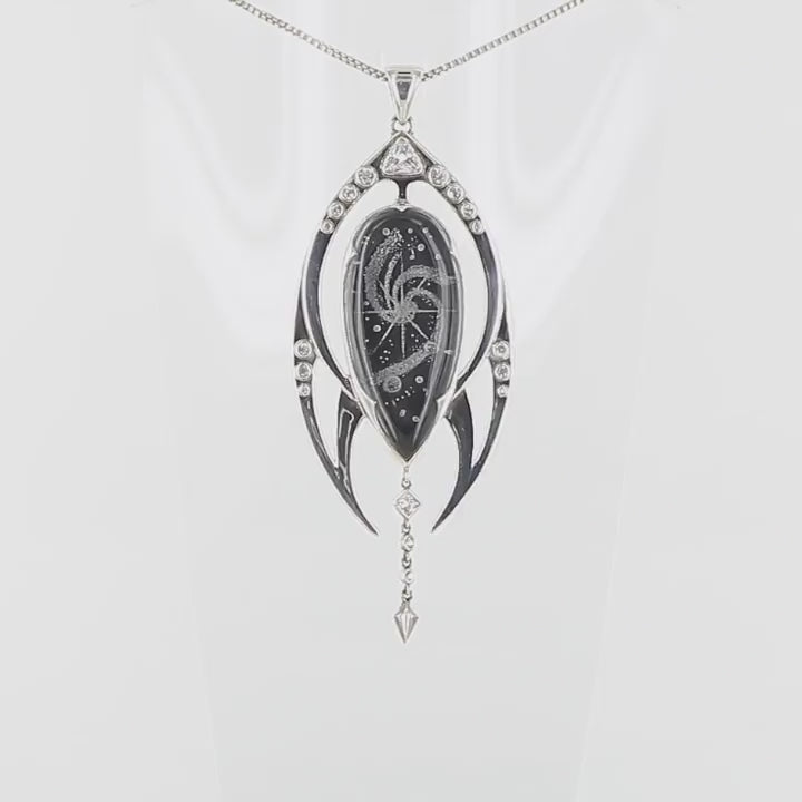 Pendentif luxueux en argent massif 925 présente un cristal de roche gravé en négatif d'une galaxie, sublimé par une tranche d'onyx noir créant un contraste saisissant. La monture en argent massif, aux lignes fluides évoquant le mouvement cosmique, enveloppe délicatement la pierre centrale.Des topazes blanches étincelantes, serties avec précision, illuminent cette création céleste comme des étoiles dans la nuit.Bijoux présenté dans un coffret de notre marque.Livraison offerte, certificat d'authenticité