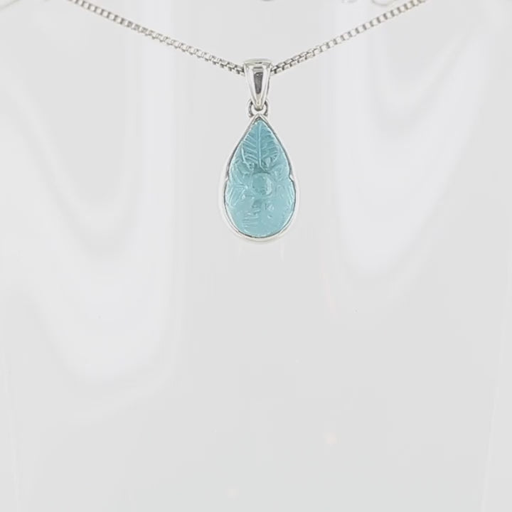 vidéo panoramique d'un pendentif pour femme en argent massif serti d'une topaze bleue sculptée de motifs floraux. Pierre cabochon en forme de goutte de couleur bleu ciel lumineux. Bijoux unique, éthique et durable présenté dans un coffret de notre marque, prêt à offrir. Livraison offerte, certificat d'authenticité, service client.