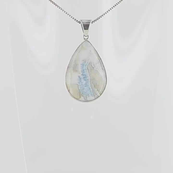 Pendentif pour femme en argent massif sertie d'une scheelite bleue. Pierre naturelle de couleur bleu, beige crème et blanc, de qualité opaque. Bijoux unique, éthique et durable présenté dans un coffret de notre marque, prêt à offrir. Livraison offerte, certificat d'authenticité, service client.