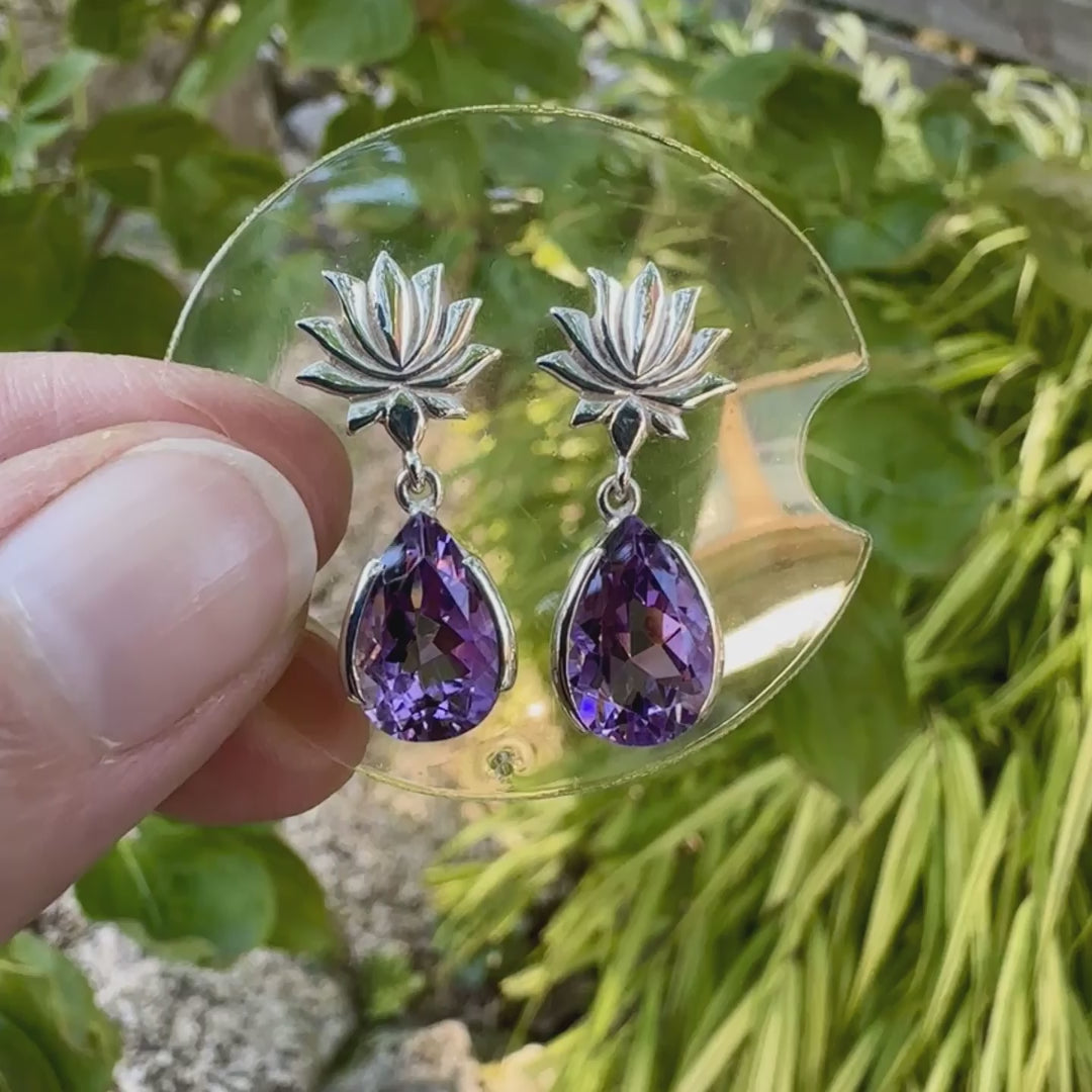 Boucles d'oreilles Lotus pour femme en argent massif serties d'Améthystes. Pierres facettées en forme de gouttes de qualités transparentes, propre à l'oeil. Pierres naturelles de couleurs violettes moyen. Bijoux unique, éthique et durable présenté dans un coffret de notre marque, prêt à offrir. Livraison offerte, certificat d'authenticité, service client.