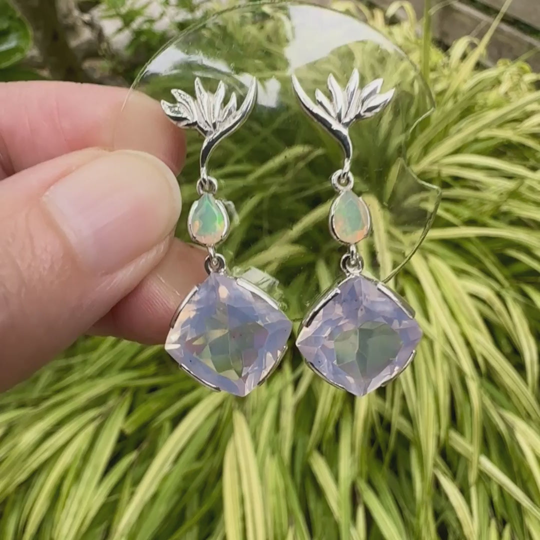Boucles d'oreilles Strelitzia pour femme en argent massif sertie de Quartz lavandes et d'opales d'Éthiopie. Pierres facettées de forme ovales et de gouttes de qualités transparentes, propre à l'oeil. Pierres naturelles de couleurs violettes pastel teintées de rose avec des reflets opalescents et multicolores pour les opales . Bijoux unique, éthique et durable présenté dans un coffret de notre marque, prêt à offrir. Livraison offerte, certificat d'authenticité, service client.