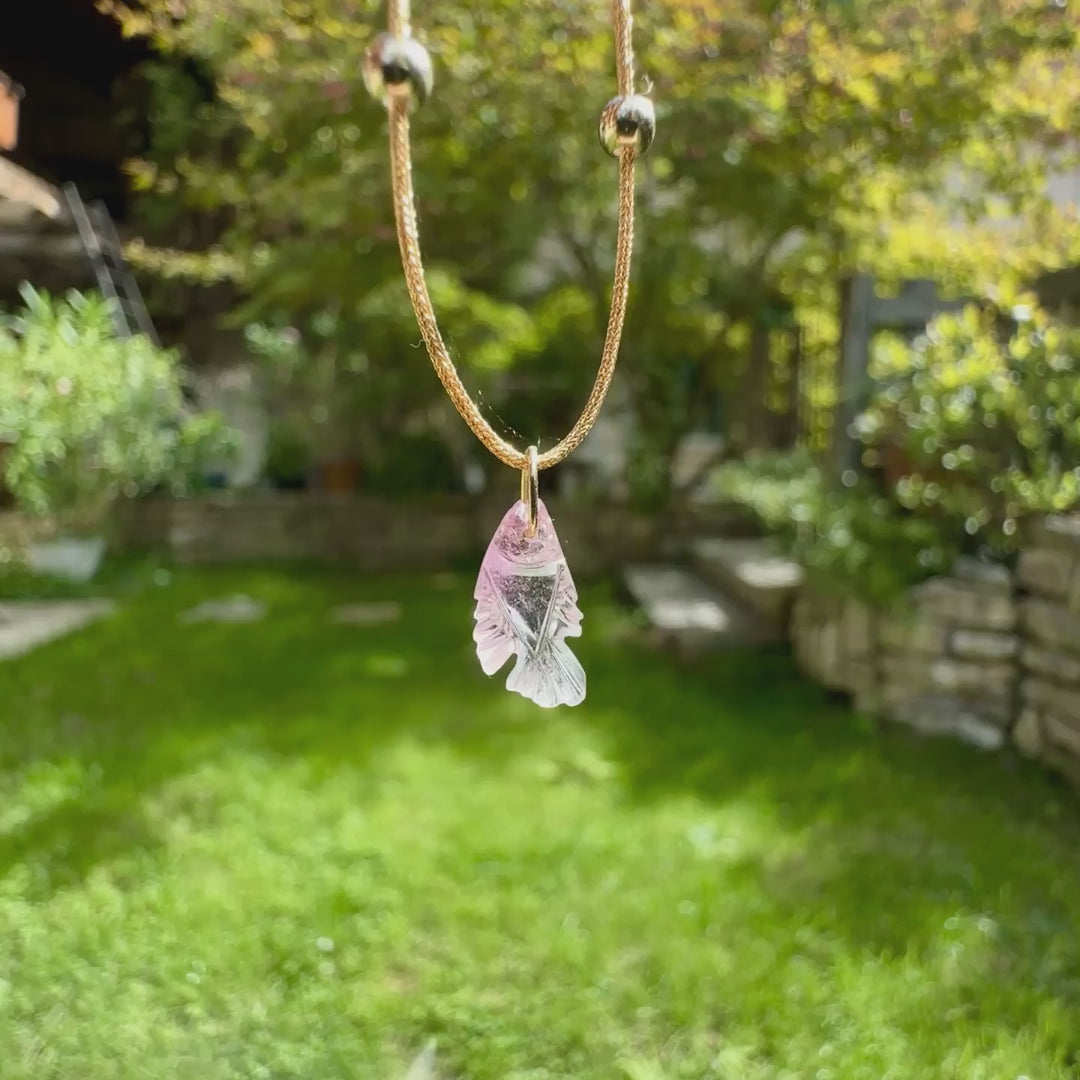 Collier pour femme orné d'une tourmaline rose sculptée à la main en 3 dimensions en forme de poisson sertie en or 18k. Le pendentif est monté sur un collier corde doré scintillant, les apprêts utilisé sont en Gold filled ( or laminé ). Longueur ajustable de 40 cm à 45 cm. Bijoux unique, éthique et durable présenté dans un coffret de notre marque, prêt à offrir. Livraison offerte, certificat d'authenticité, service client.