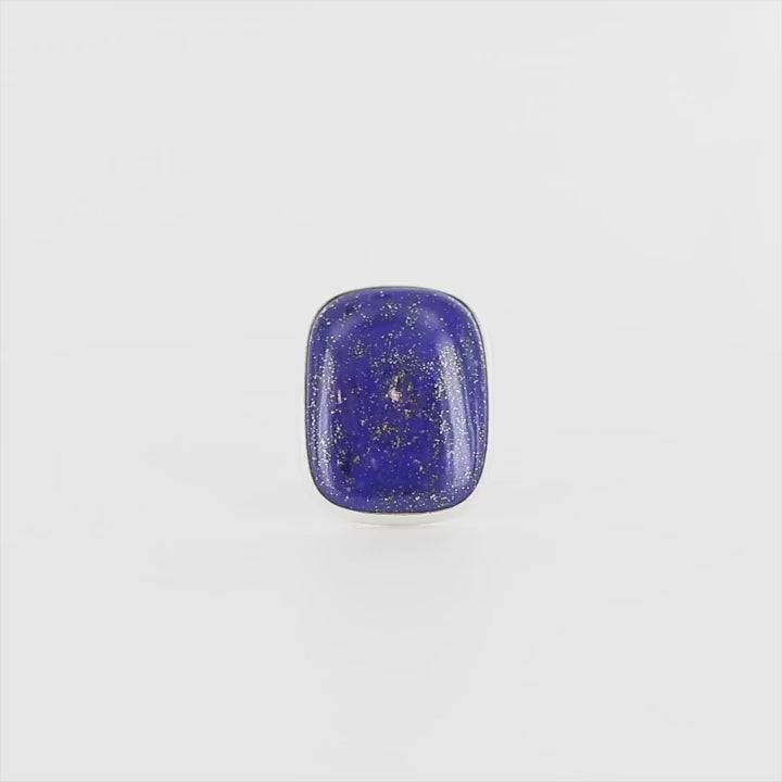 Bague en argent massif ornée d'un lapis lazuli de forme rectangulaire aux angles arrondis. La pierre présente une couleur bleu profond mouchetée de fines inclusions dorées de pyrite. Le sertissage est lisse et épuré, encadrant parfaitement la pierre, mettant en valeur son éclat naturel et sa texture minérale. Un bague élégante et sobre. Bijoux unique, éthique et durable présenté dans un coffret de notre marque, prêt à offrir. Livraison offerte, certificat d'authenticité, service client.