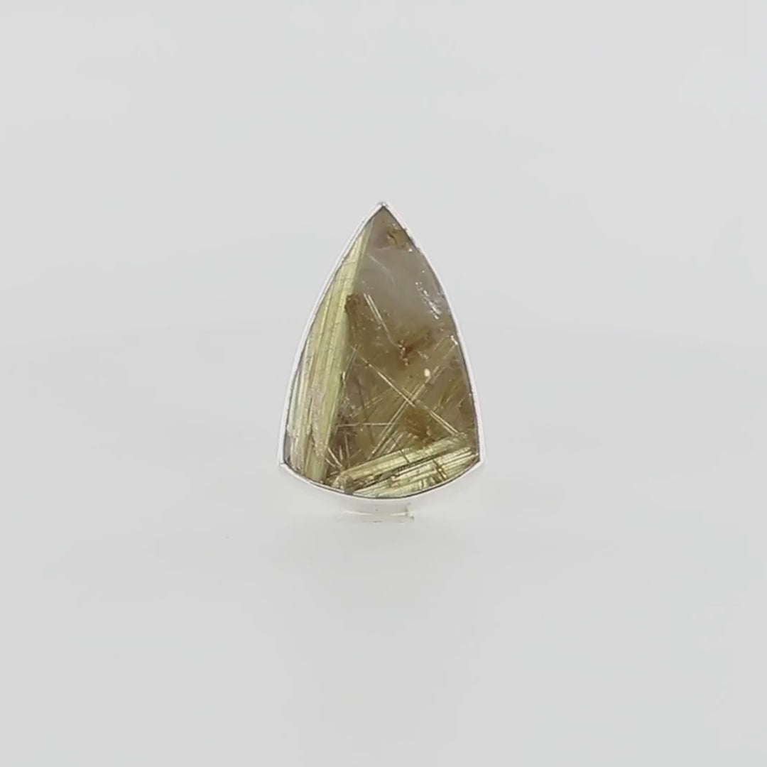 Grande bague en argent massif ornée d’un quartz rutile doré taillé en forme de bouclier allongé, aux inclusions fibreuses dorées bien visibles, formant un motif graphique complexe sous la surface brillante de la pierre. Le serti lisse suit fidèlement les contours de la gemme, mettant en valeur sa transparence et ses reflets dorés. Bijoux unique, éthique et durable présenté dans un coffret de notre marque, prêt à offrir. Livraison offerte, certificat d'authenticité, service client.