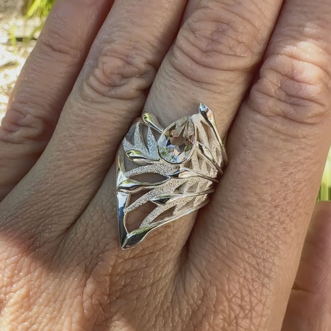 Grande Bague Jungle illustrant un feuillage tropicale, pour femme, en argent massif sertie d'une Topaze blanche facettée en forme de goutte. Pierre incolore, très lumineuse et propre à l'oeil. Disponible en plusieurs tailles. Bijoux unique, éthique et durable présenté dans un coffret de notre marque, prêt à offrir. Livraison offerte, certificat d'authenticité, service client.