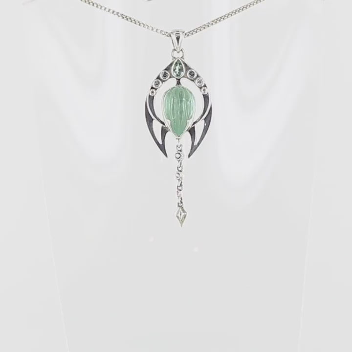 Pendentif pour femme en argent massif serti d'un cabochon d'Aigue marine de couleur bleu vert sculpté en forme de bouton de fleur. D'autres Tourmalines et Goshénites ornent ce bijou. Pendentif de créateur, contemporain, unique et original, aux formes éthérées et épurées. Bijoux unique, éthique et durable présenté dans un coffret de notre marque, prêt à offrir. Livraison offerte, certificat d'authenticité, service client.