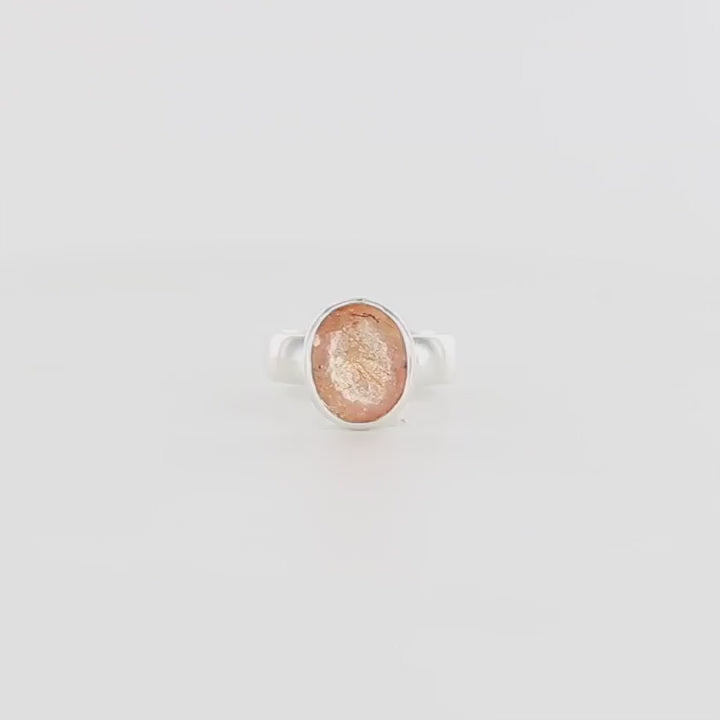 Bague de créateur en argent massif pour femme sertie d'une magnifique pierre de soleil. Pierre facettée de forme ovale de qualité transparente. Pierre naturelle de couleur orange à scintillement doré. Bague réalisée en taille 56. Bijoux unique, éthique et durable présenté dans un coffret de notre marque, prêt à offrir. Livraison offerte, certificat d'authenticité, service client.