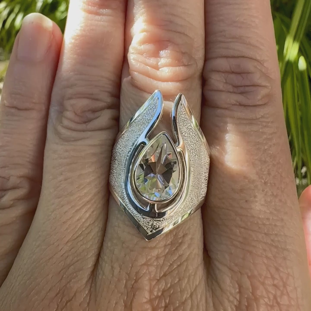 Grande bague pour femme en argent massif sertie d'une Topaze blanche, collection Bastet. Pierre facettée en forme de goutte, pierre naturelle incolore avec un très bel éclat. Pierre fine de qualité transparente propre à l'oeil. Disponible en plusieurs tailles. Bijoux unique, éthique et durable présenté dans un coffret de notre marque, prêt à offrir. Livraison offerte, certificat d'authenticité, service client.
