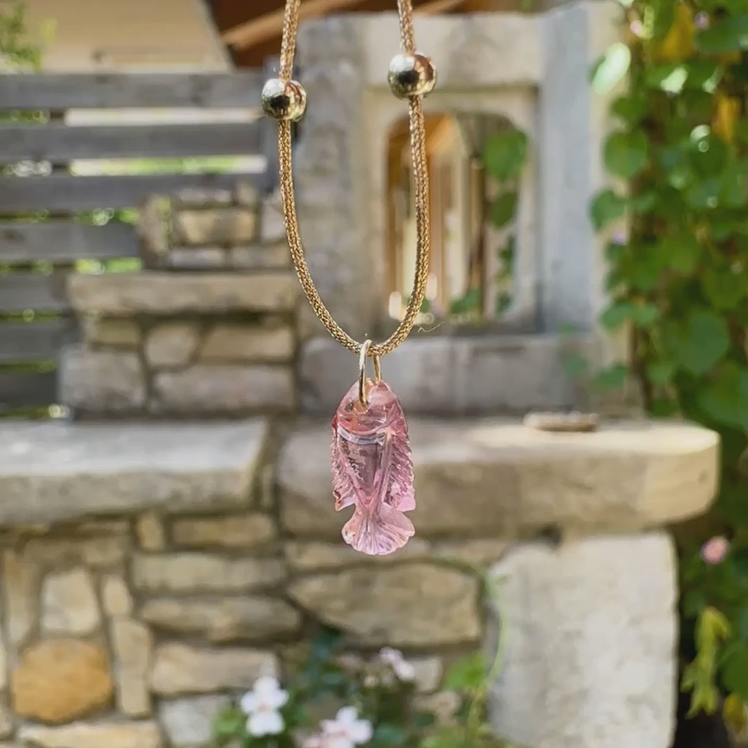 Collier pour femme orné d'une tourmaline rose sculptée à la main en 3 dimensions en forme de poisson sertie en or 18k. Le pendentif est monté sur un collier corde doré scintillant, les apprêts utilisé sont en Gold filled ( or laminé ). Longueur ajustable de 40 cm à 45 cm. Bijoux unique, éthique et durable présenté dans un coffret de notre marque, prêt à offrir. Livraison offerte, certificat d'authenticité, service client.