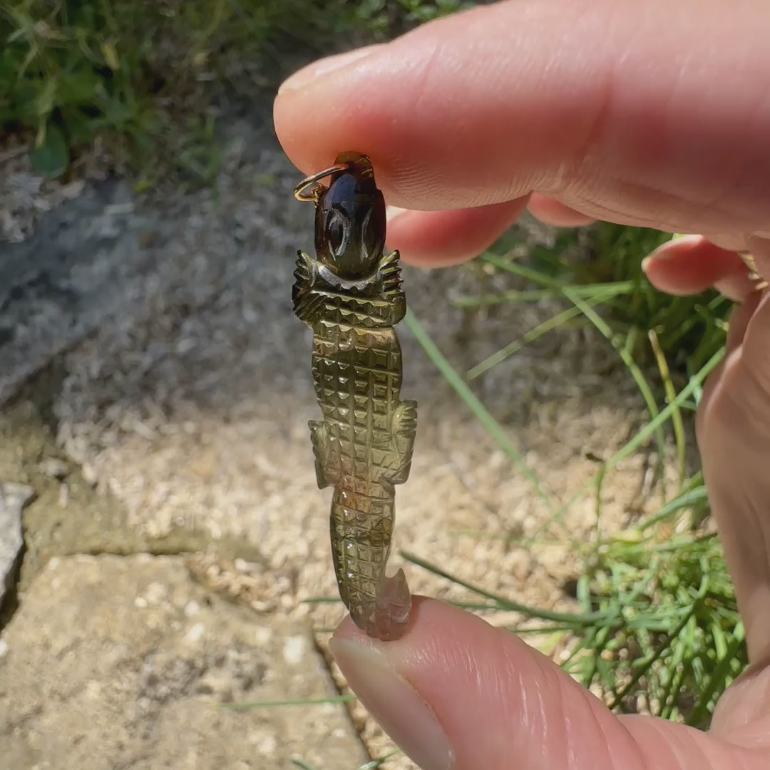 Collier pour homme orné d'une tourmaline melon d'eau sculptée à la main en 3 dimensions en forme de crocodile sertie en or 18k. Le pendentif est vendu sur une chaine de 45 cm de long en Gold filled ( or laminé ). Bijoux unique, éthique et durable présenté dans un coffret de notre marque, prêt à offrir. Livraison offerte, certificat d'authenticité, service client.