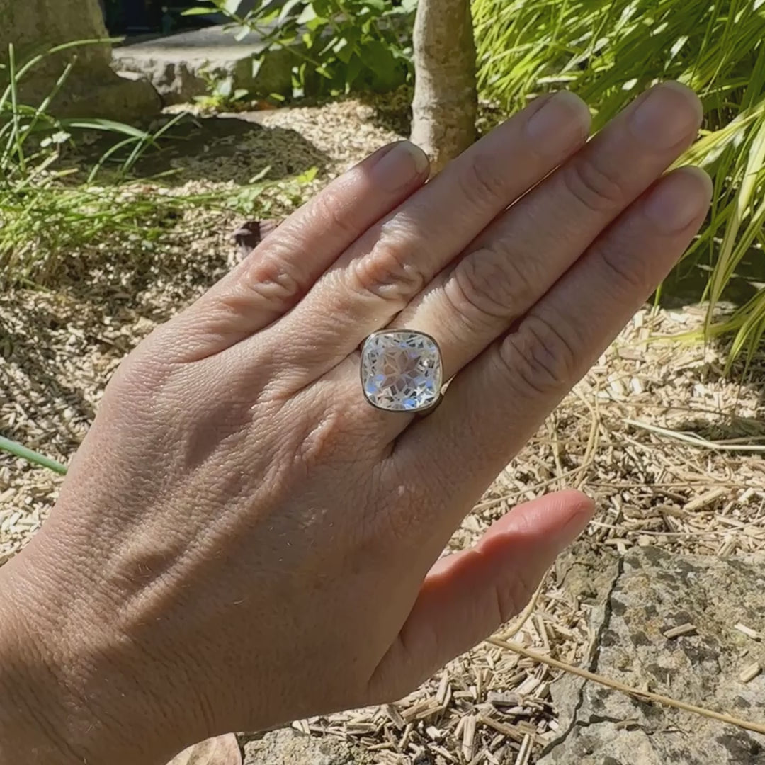 Bague cocktail pour femme en argent massif sertie d'un Cristal de roche gravé d'une fleur de vie. Pierre facettée de forme carrée de qualité transparente, propre à l'oeil. Pierre naturelle incolore et blanche sur les parties gravées. Bague réalisée en taille 60. Bijoux unique, éthique et durable présenté dans un coffret de notre marque, prêt à offrir. Livraison offerte, certificat d'authenticité, service client.