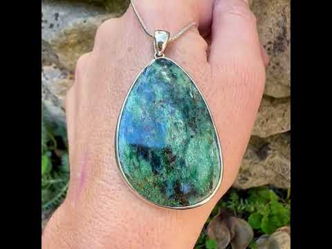 Pendentif pour femme en argent massif serti d'une pierre verte scintillante à inclusions bleutées et noires. Cabochon de forme libre de qualité opaque. Bijou unique réalisé par Orchajewelry
