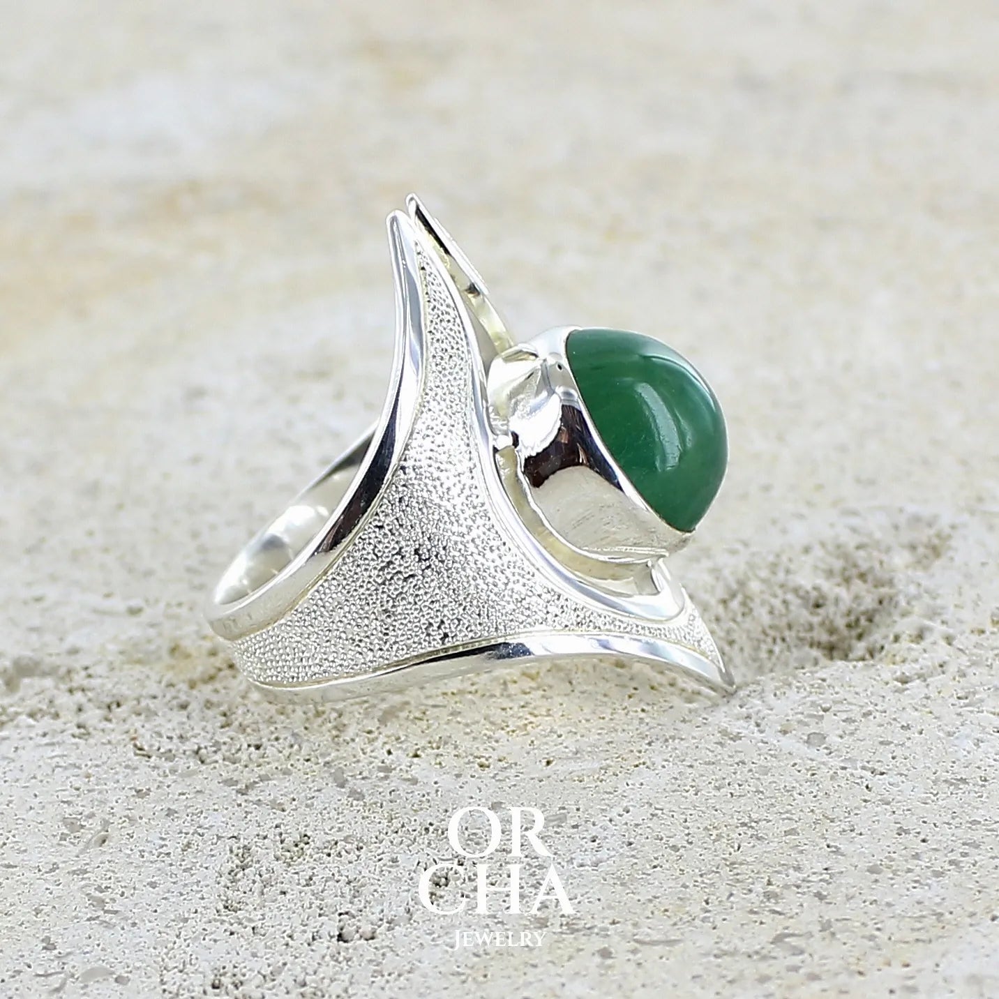 profil d'une Grande bague pour femme en argent massif sertie d'une préhnite de couleur verte jaune clair, Pierre taillée en cabochon en forme de goutte. Pierre gemme de qualité transparente à inclusions. Bijoux unique réalisé en taille 59 par Orchajewelry.