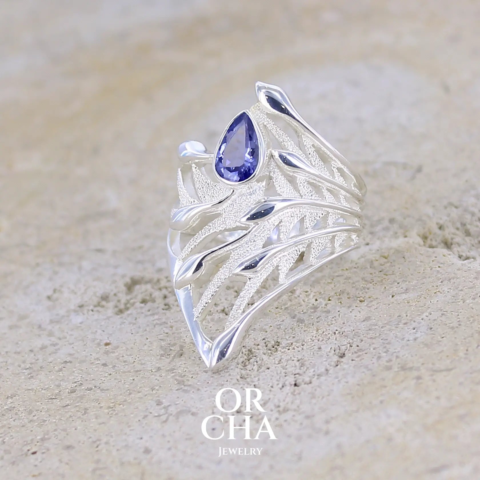 Grande Bague pour femme, feuillage tropicale travaillé en filigrane en argent massif, sertie d'une Tanzanite bleu lavande. Pierre facettée en forme de goutte. Pierre lumineuse et propre à l'oeil. Bijoux unique, éthique et durable présenté dans un coffret de notre marque, prêt à offrir. Livraison offerte, certificat d'authenticité, service client.