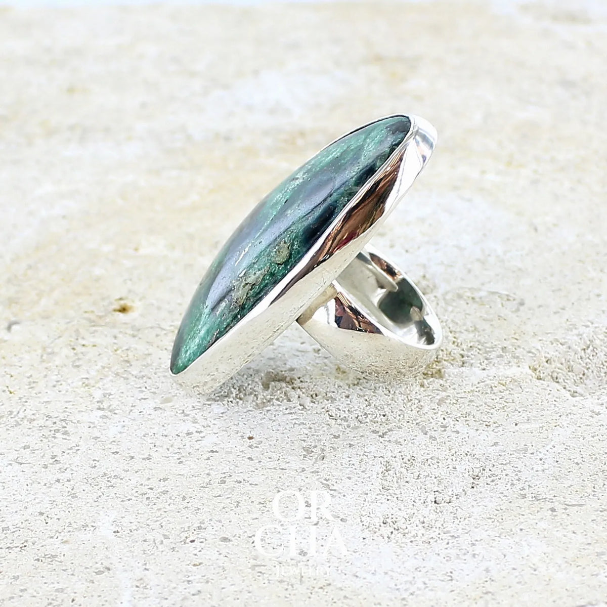 profil d'une bague pour femme en argent massif sertie d'un cabochon de pierre verte scintillante à inclusions bleues et noires. Pierre de qualité opaque et de forme libre. Bijou unique réalisée en taille 56 par Orchajewelry