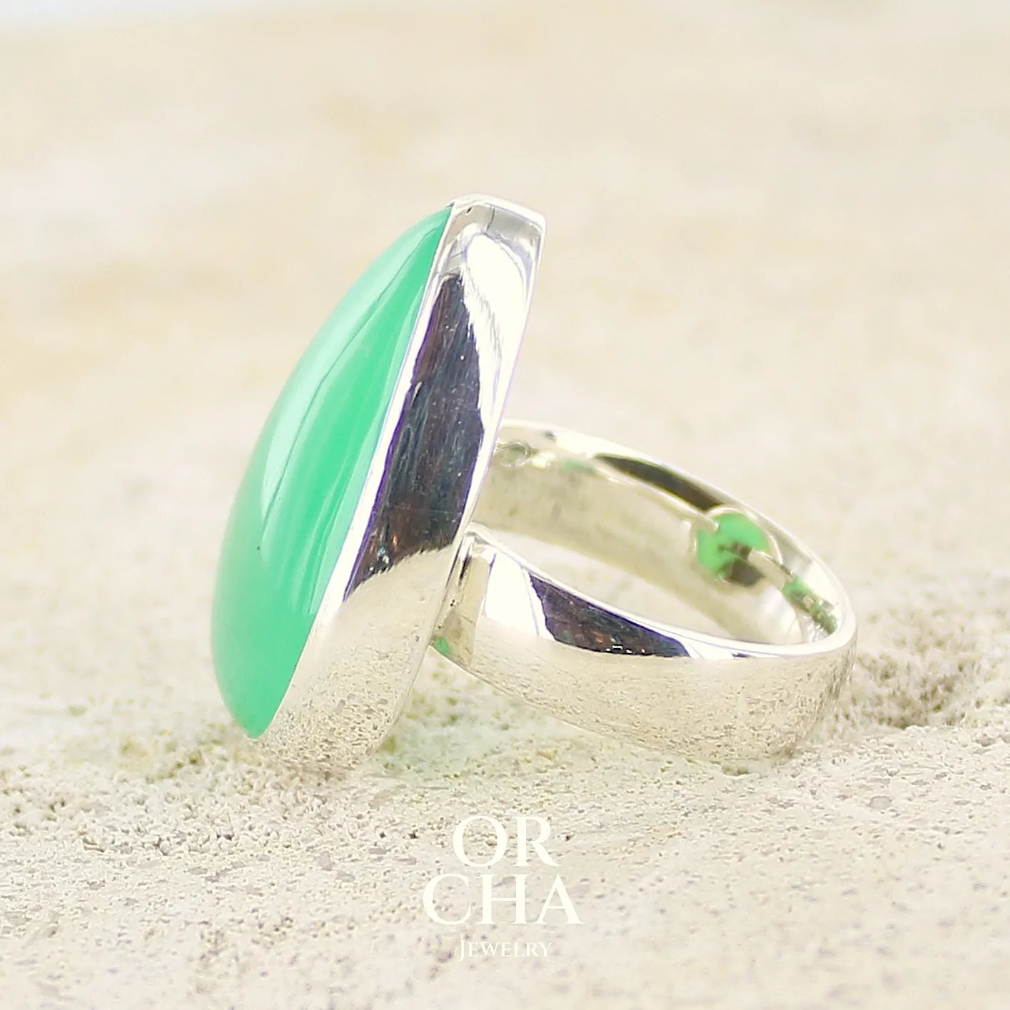 Profil d'une bague pour femme en argent massif, sertie d'un cabochon de Chrysoprase. Pierre taillée en forme de goutte de qualité opaque. Bijoux unique réalisé en taille 58 par Orcha Jewelry