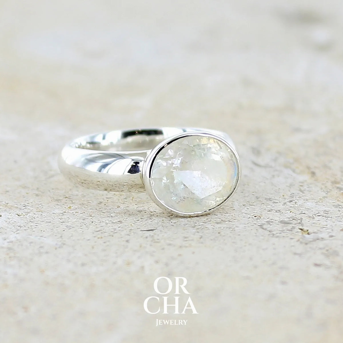 Profil droit d'une Bague cocktail pour femme en argent massif 925 sertie d'une pierre de lune arc en ciel de Madagascar taillée de 2,5 carats incolore aux reflets bleutés et arc en ciel. Pierre transparente avec inclusions. Bijoux unique réalisée en taille 56 par Orchajewelry