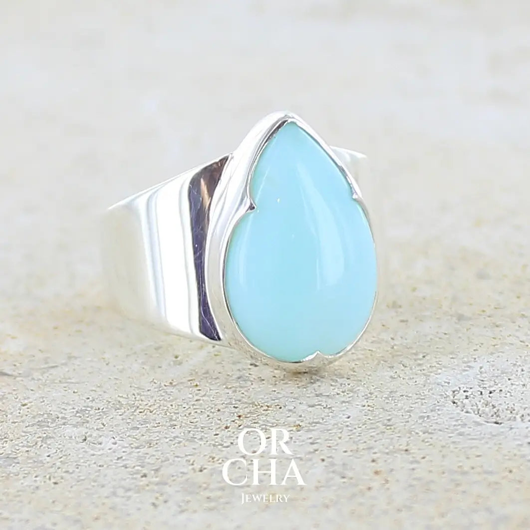 Profil droit d'une bague pour femme en argent massif, sertie d'un cabochon d'opale bleue du Pérou de couleur bleu ciel. Pierre taillée en forme de goutte de qualité opaque. Bijou unique de taille 56
