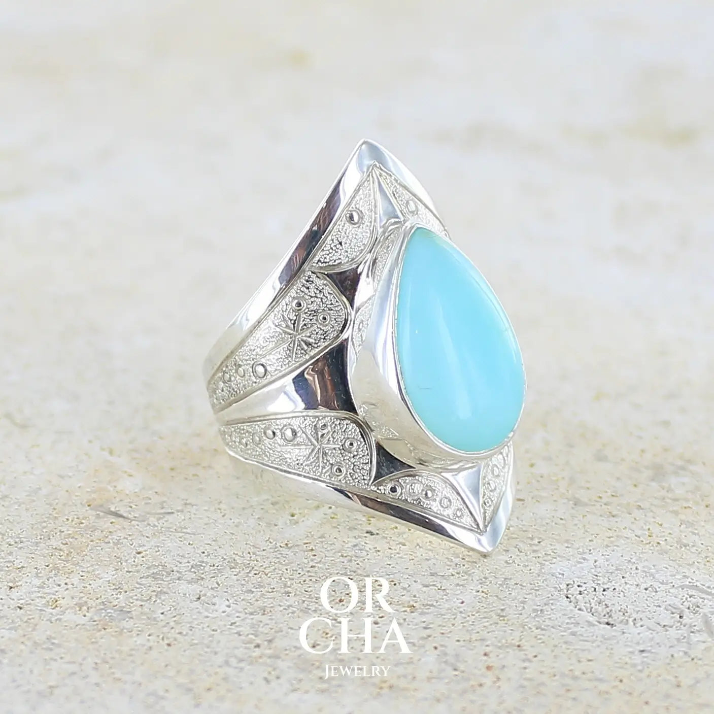 Profil droit d'une grande Bague pour femme en argent massif, sertie d'un cabochon d'opale bleue du Pérou de couleur bleu ciel turquoise. Pierre taillée en forme de goutte. de qualité opaque. bijou unique réalisé en taille 52.
