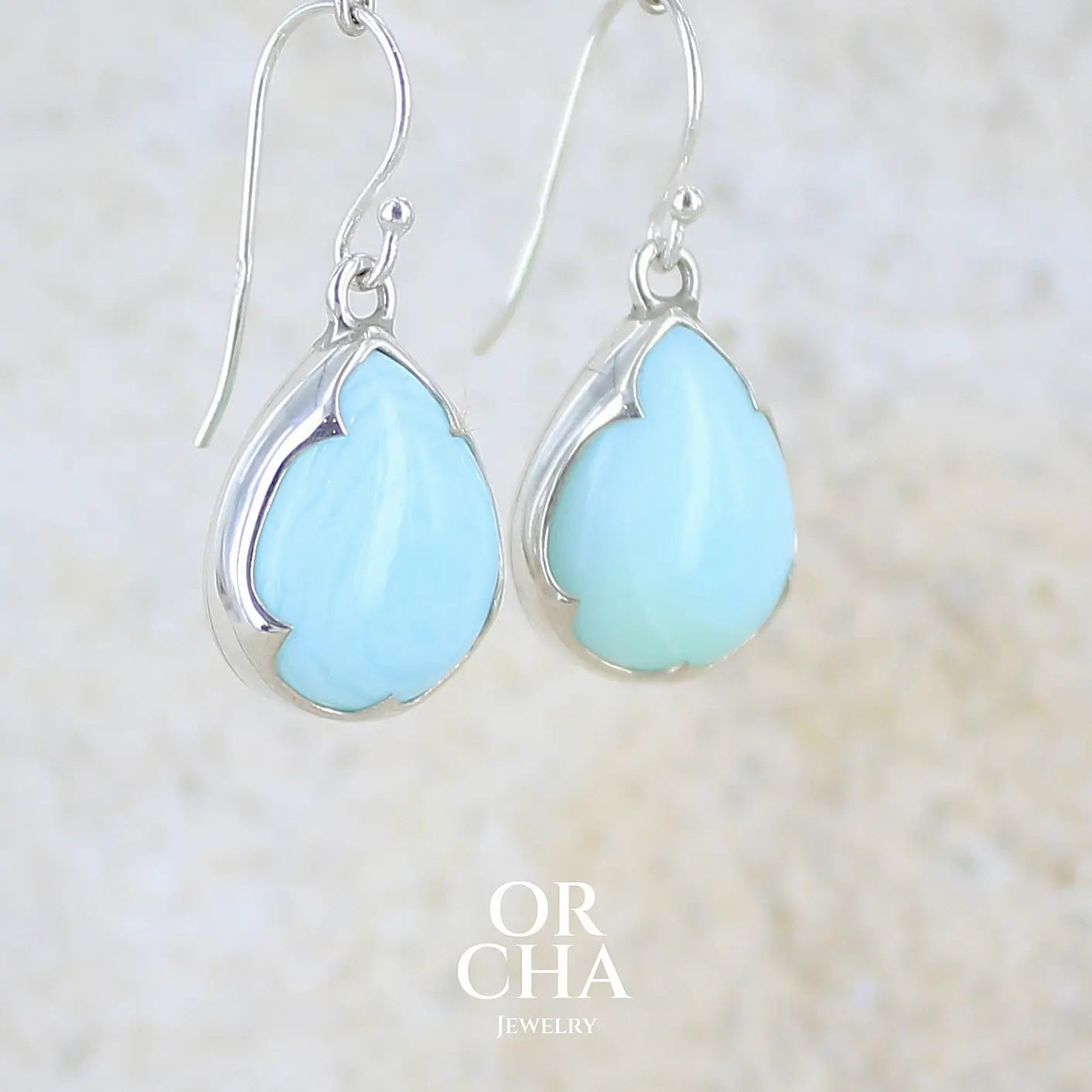 profil droit de boucles d'oreilles pendantes en argent massif serties d'opale bleue du Pérou. Pierres cabochon taillée en goutte de qualité opaque. Pierre naturelle de couleur bleu ciel. Bijoux unique, éthique et durable présenté dans un coffret de notre marque, prêt à offrir. Livraison offerte, certificat d'authenticité, service client.