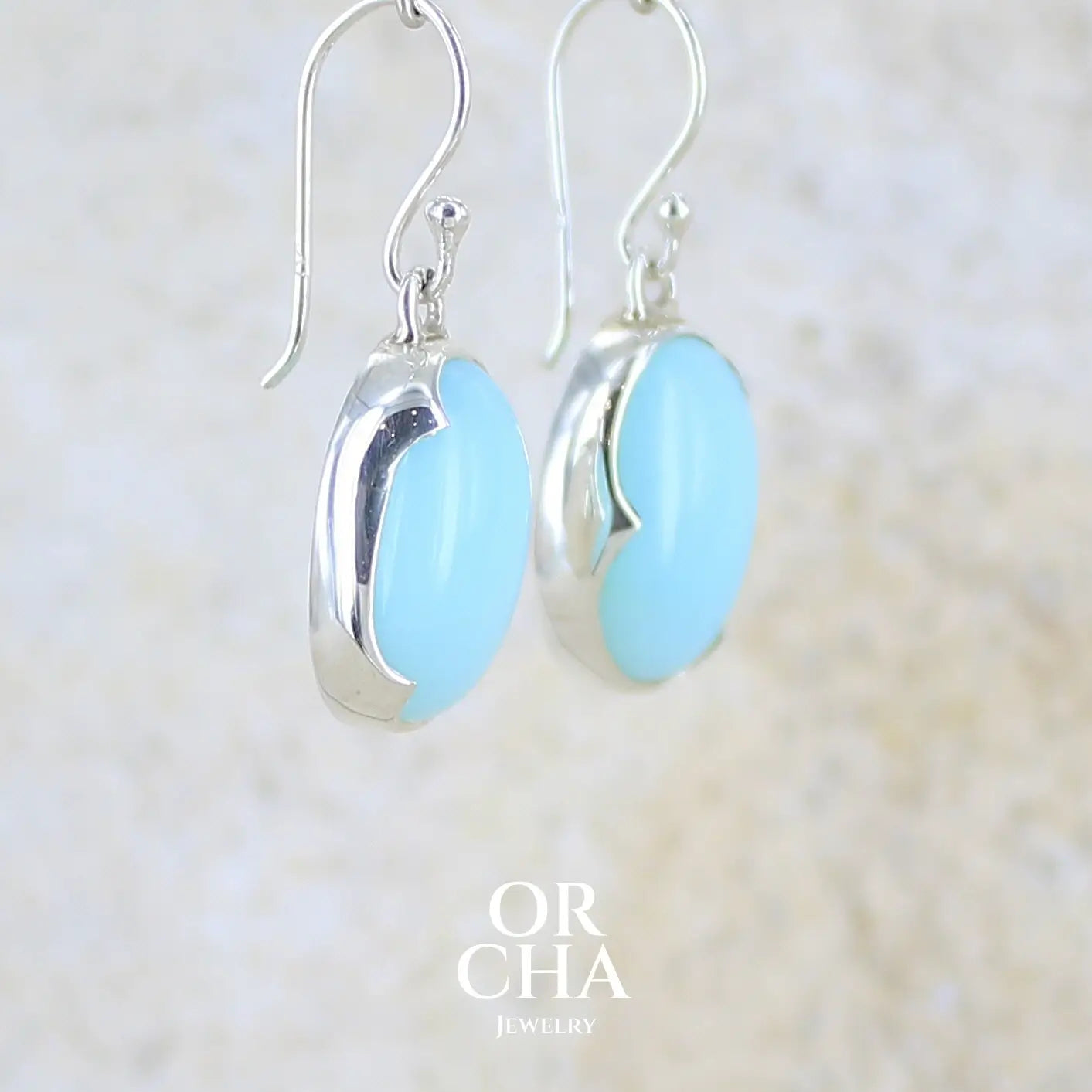 profil droit boucles d'oreilles pendantes en argent massif serties d'opale bleue du Pérou. Pierres cabochon taillée en ovale de qualité opaque. Pierre naturelle de couleur bleu ciel. Bijoux unique, éthique et durable présenté dans un coffret de notre marque, prêt à offrir. Livraison offerte, certificat d'authenticité, service client.