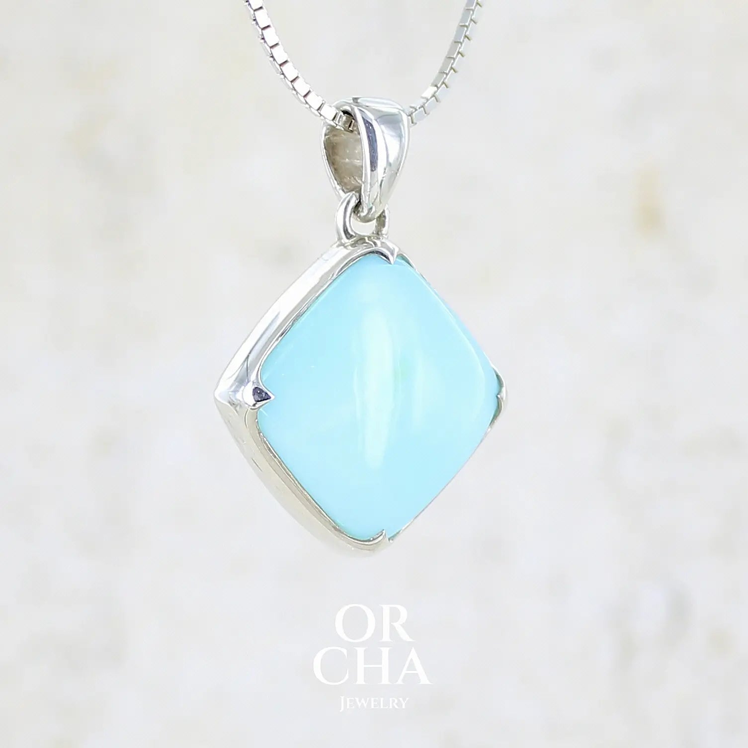 profil droit d'un pendentif en argent massif, sertie d'un cabochon d'opale bleue du Pérou de couleur bleu ciel clair. Pierre de forme carrée. Pierre opaque. Bijoux unique, éthique et durable présenté dans un coffret de notre marque, prêt à offrir. Livraison offerte, certificat d'authenticité, service client.