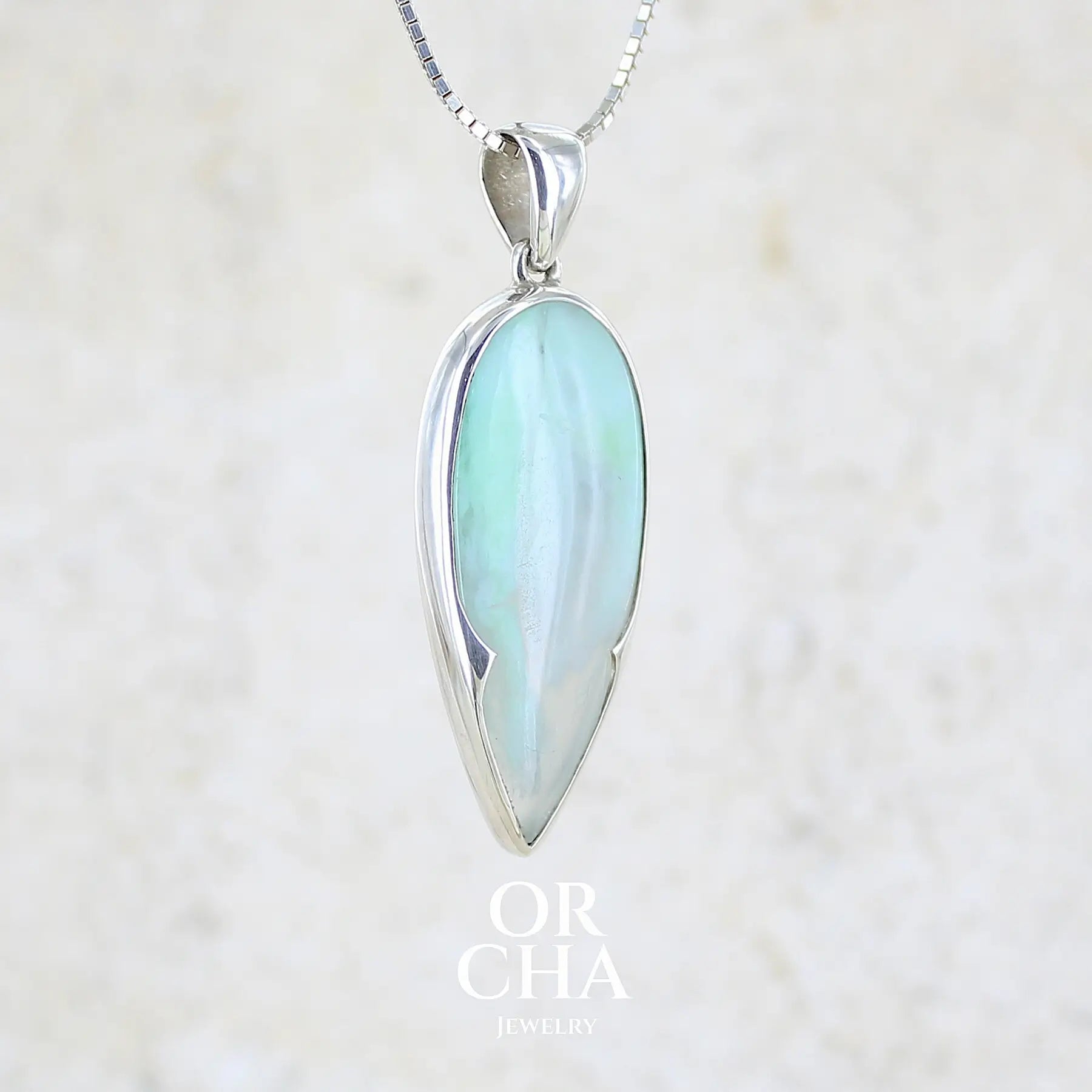 profil droit d'un pendentif pour femme et homme en argent massif, sertie d'un cabochon d'opale bleue du Pérou de couleur verte bleutée. Pierre en forme de goutte inversée. Pierre opaque et translucide. Bijoux unique, éthique et durable présenté dans un coffret de notre marque, prêt à offrir. Livraison offerte, certificat d'authenticité, service client.