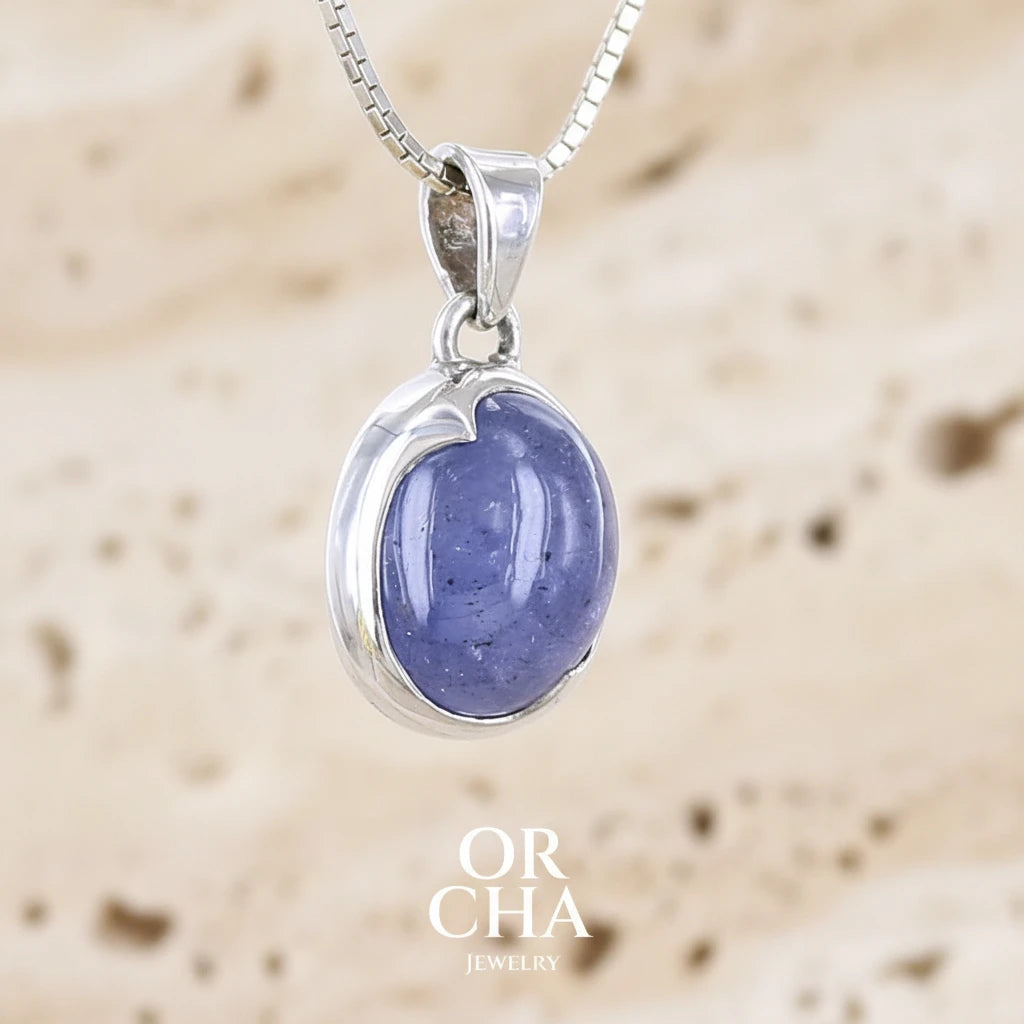 profil droit d'un pendentif pour femme en argent massif serti d'un cabochon de Tanzanite de couleur bleu lavande . Pierre translucide présentant des inclusions. Pierre ayant subit un traitement de chauffe, traitement admis et fréquent en gemmologie pour ce type de pierre . Bijoux unique, éthique et durable présenté dans un coffret de notre marque, prêt à offrir. Livraison offerte, certificat d'authenticité, service client.