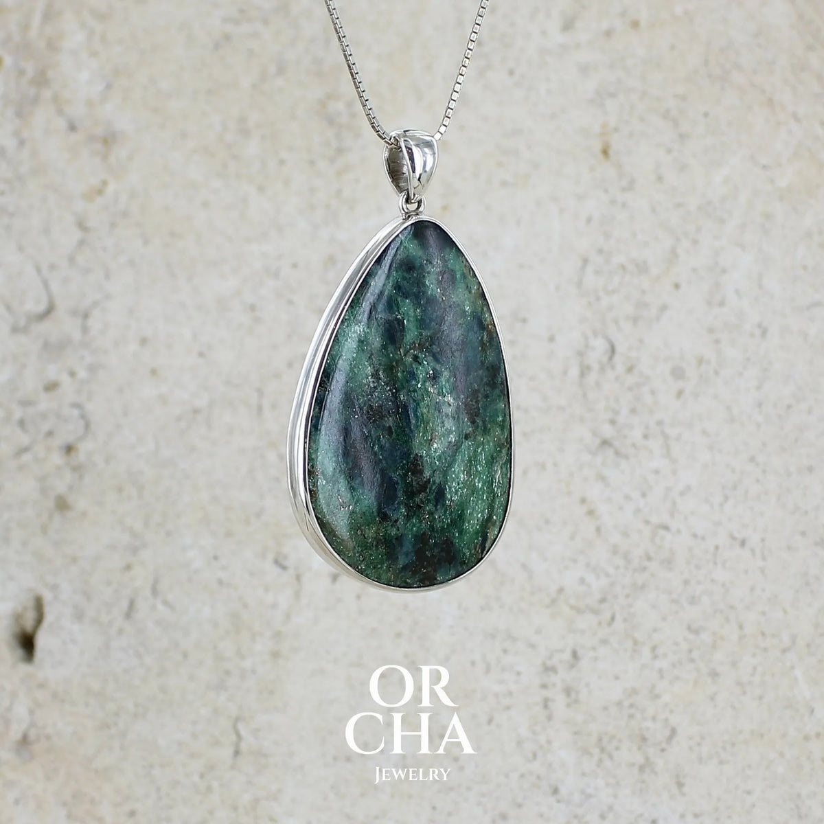 profil droit d'un pendentif pour femme en argent massif serti d'une pierre verte scintillante à inclusions bleutées et noires. Cabochon de forme libre de qualité opaque. Bijou unique réalisé par Orchajewelry