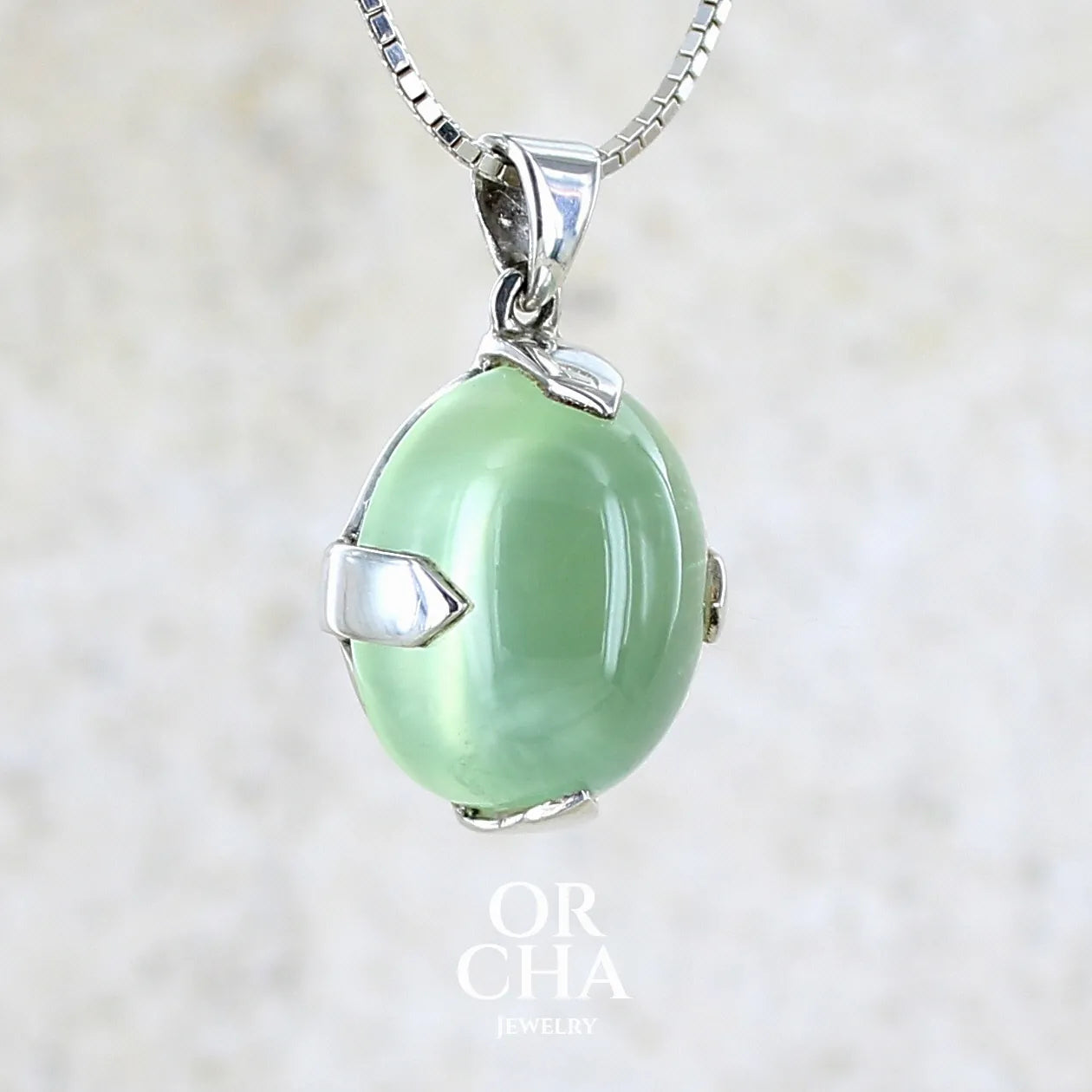 profil gauche d'une Pendentif ovale en argent massif, serti d'un cabochon de préhnite de couleur verte clair. Pierre de qualité translucide comportant des inclusions. Bijoux unique par Orcha Jewelry