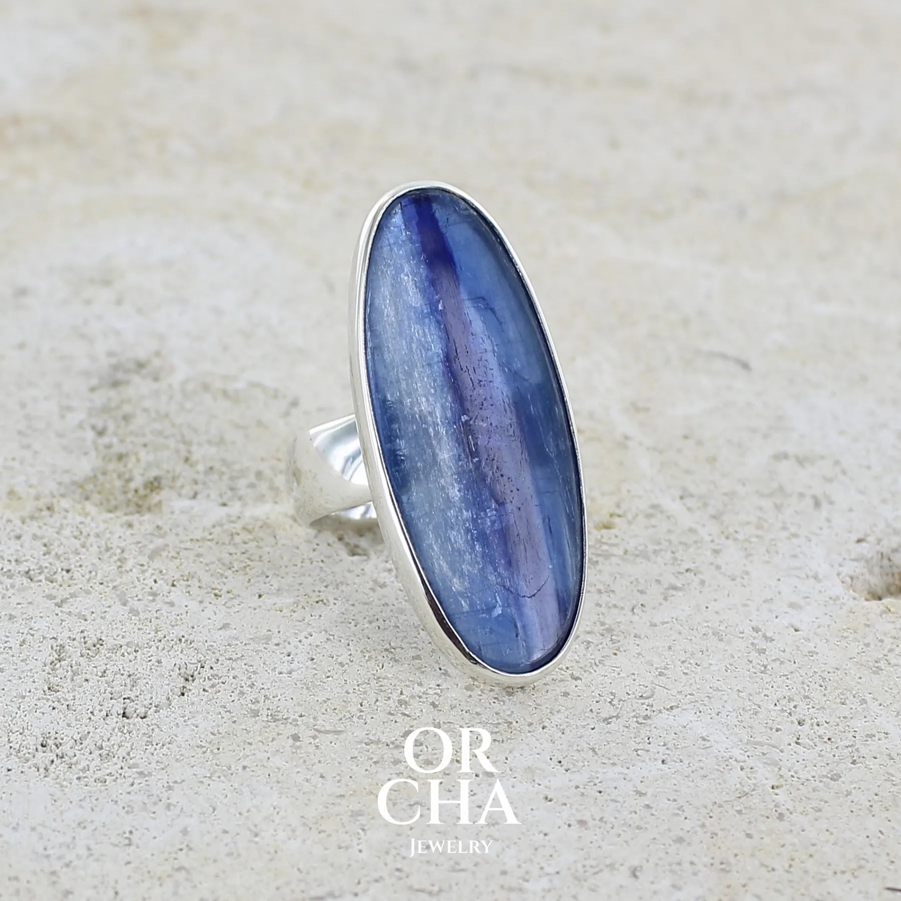 profil gauche d'une grande Bague pour femme en argent massif, sertie d'un long cabochon ovale de cyanite de couleur bleu denim nacré. Pierre de qualité translucide. Bijou unique réalisée en taille 58 par Orcha jewelry