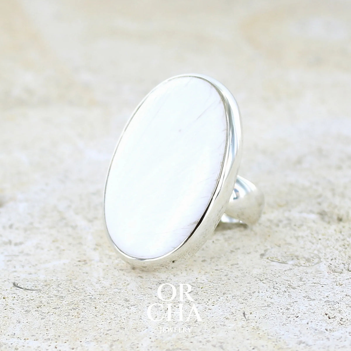 profil gauche d'une bague pour femme en argent massif sertie d'un cabochon de scolecite de couleur blanc pur. Pierre naturelle de qualité opaque taillée en ovale. Bague unique réalisée en taille 58 par Orcha jewelry