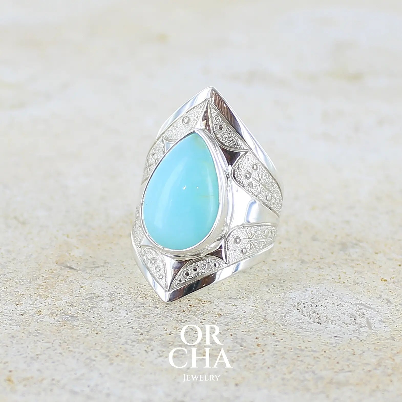 Profil gauche d'une grande Bague pour femme en argent massif, sertie d'un cabochon d'opale bleue du Pérou de couleur bleu ciel turquoise. Pierre taillée en forme de goutte. de qualité opaque. bijou unique réalisé en taille 52.