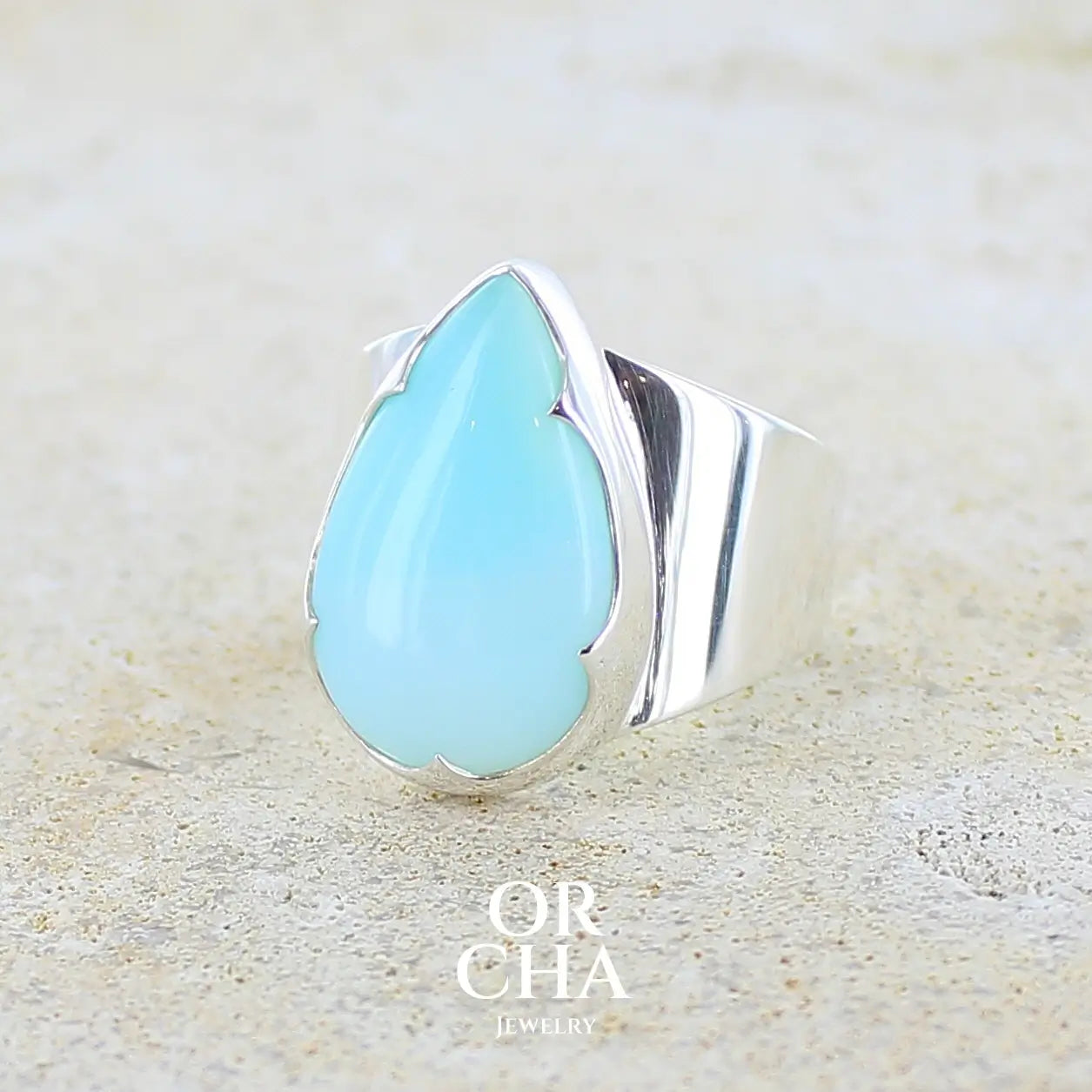 profil gauche d'une bague pour femme en argent massif, sertie d'un cabochon d'opale bleue du Pérou de couleur bleu ciel. Pierre taillée en forme de goutte de qualité opaque. Bijou unique réalisé en taille 58.