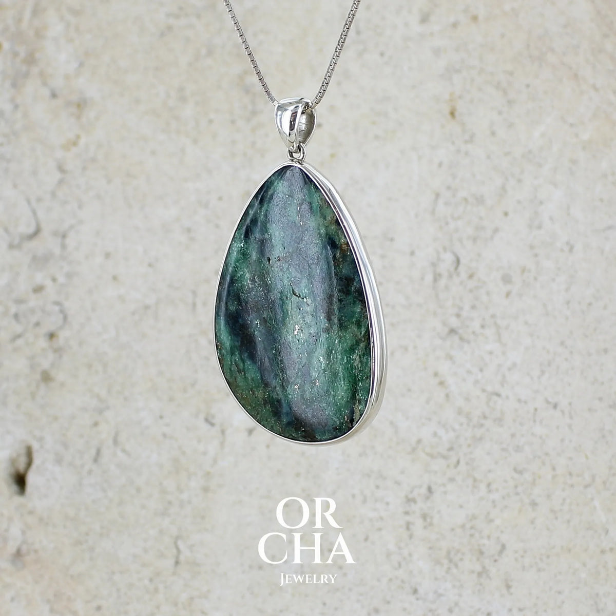 profil gauche d'un pendentif pour femme en argent massif serti d'une pierre verte scintillante à inclusions bleutées et noires. Cabochon de forme libre de qualité opaque. Bijou unique réalisé par Orchajewelry