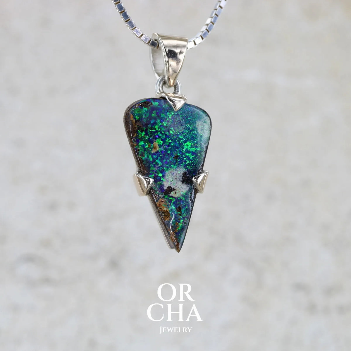 profil d'un pendentif pour homme en or 9k et argent massif 925 serti d'une opale boulder aux feux multicolores bleus et verts. Tranche d'opale massive naturelle taillée en forme d'aile. Pierre de qualité opaque originaire d'Australie. Bijoux unique par Orcha Jewelry.