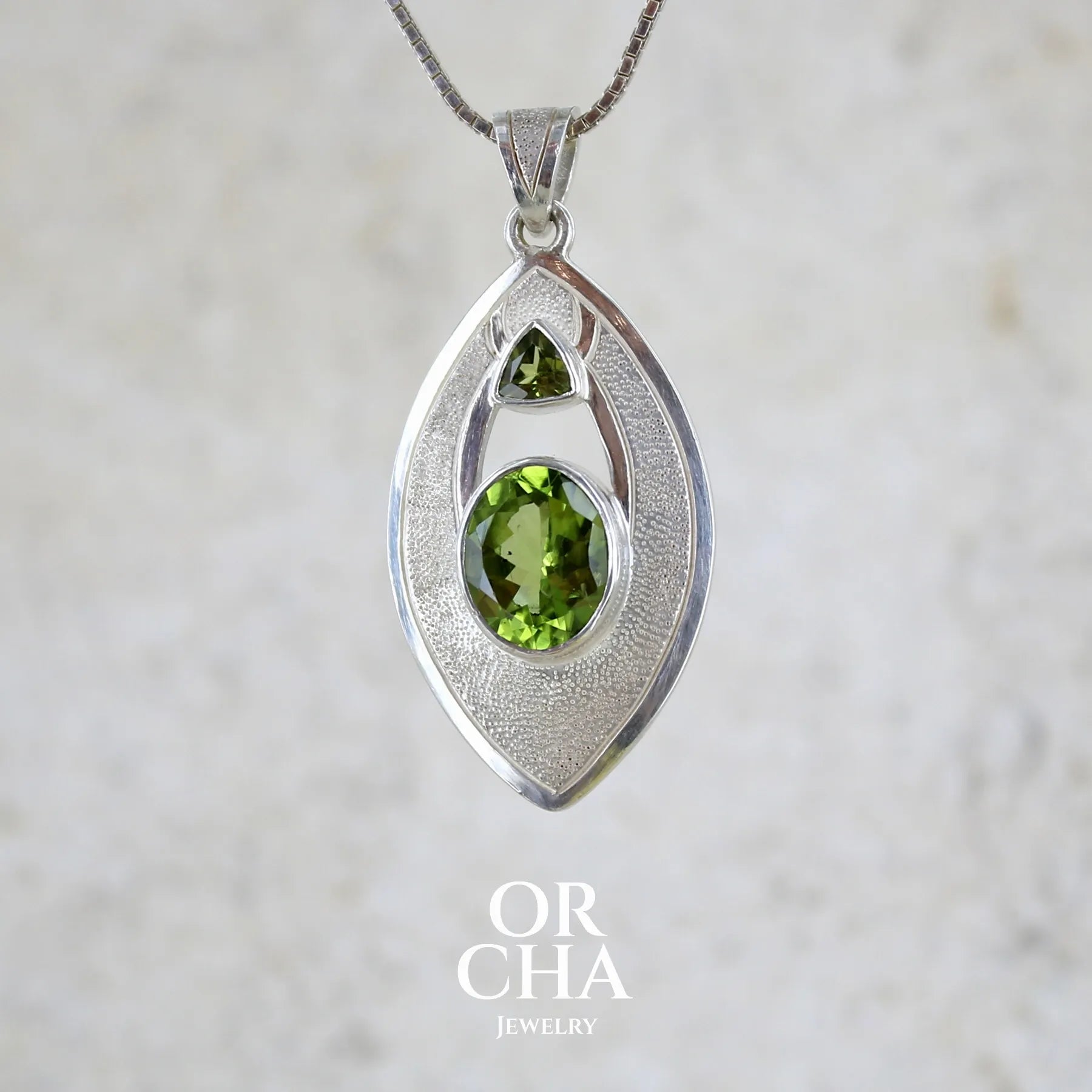 profil gauche d'un pendentif pour femme en argent massif serti d'un péridot de couleur vert olive doré intense. Pierre taillée, de forme ovale, transparente propre à l'oeil. Bijou unique réalisé par Orchajewelry