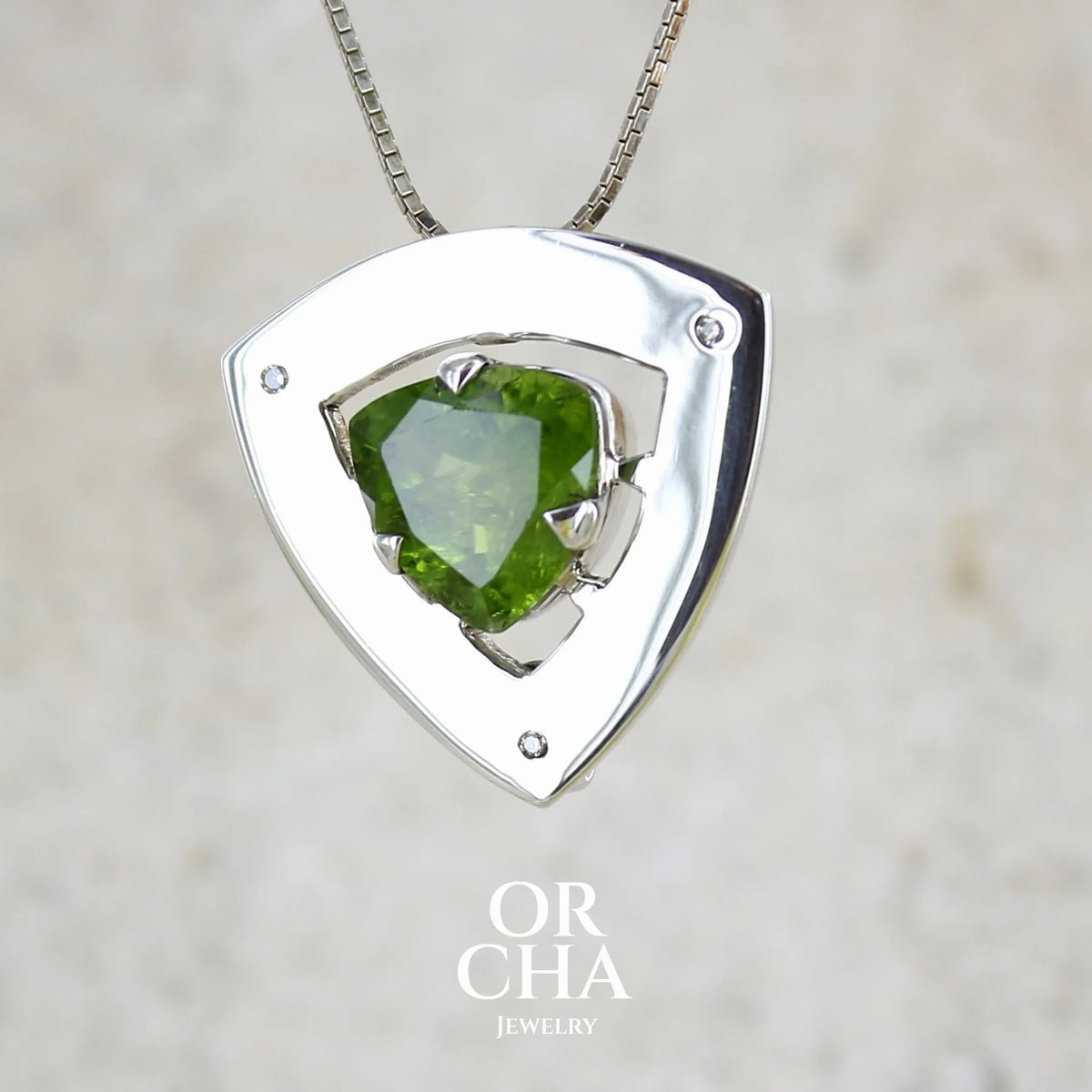 profil d'un pendentif contemporain pour femme en argent massif serti d'un péridot de couleur vert olive doré intense et de petits diamants. Pierre taillée, de forme triangulaire, transparente présentant de nombreuse inclusions. Bijou unique réalisé par Orchajewelry