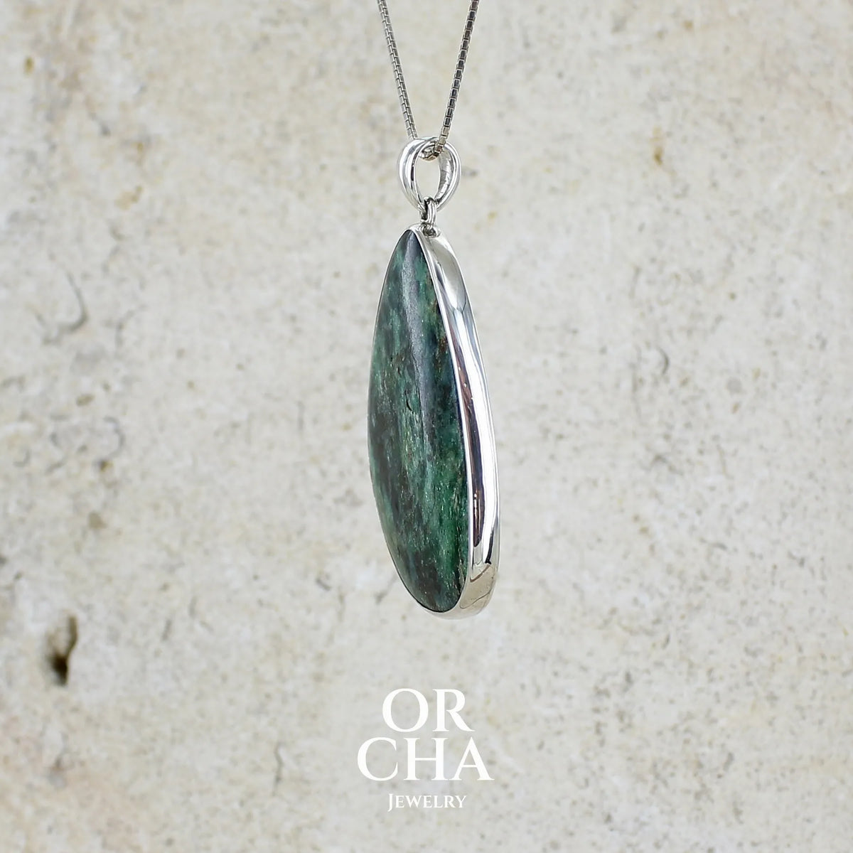 profil d'un pendentif pour femme en argent massif serti d'une pierre verte scintillante à inclusions bleutées et noires. Cabochon de forme libre de qualité opaque. Bijou unique réalisé par Orchajewelry