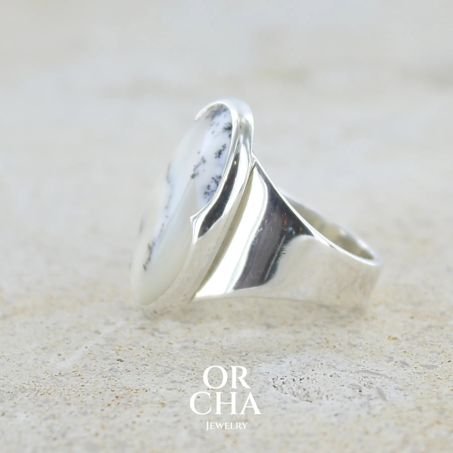 Détail du sertissage d'une bague pour femme en argent massif sertie d'un cabochon ovale d'agate dendritique de couleur blanc pur et noir. Pierre opaque translucide à inclusions paysages de dendrites de manganèse noires contrastées. Bijou unique réalisé en taille 54 par Orchajewelry