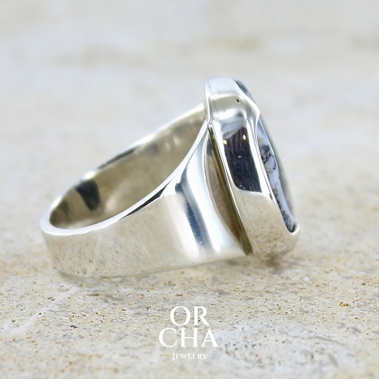 détail du sertissage d'une bague pour femme en argent massif sertie d'un cabochon ovale d'agate dendritique de couleur blanc pur et noir. Pierre opaque translucide à inclusions paysages de dendrites de manganèse noires contrastées. Bijou unique réalisée en taille 54 par Orchajewelry