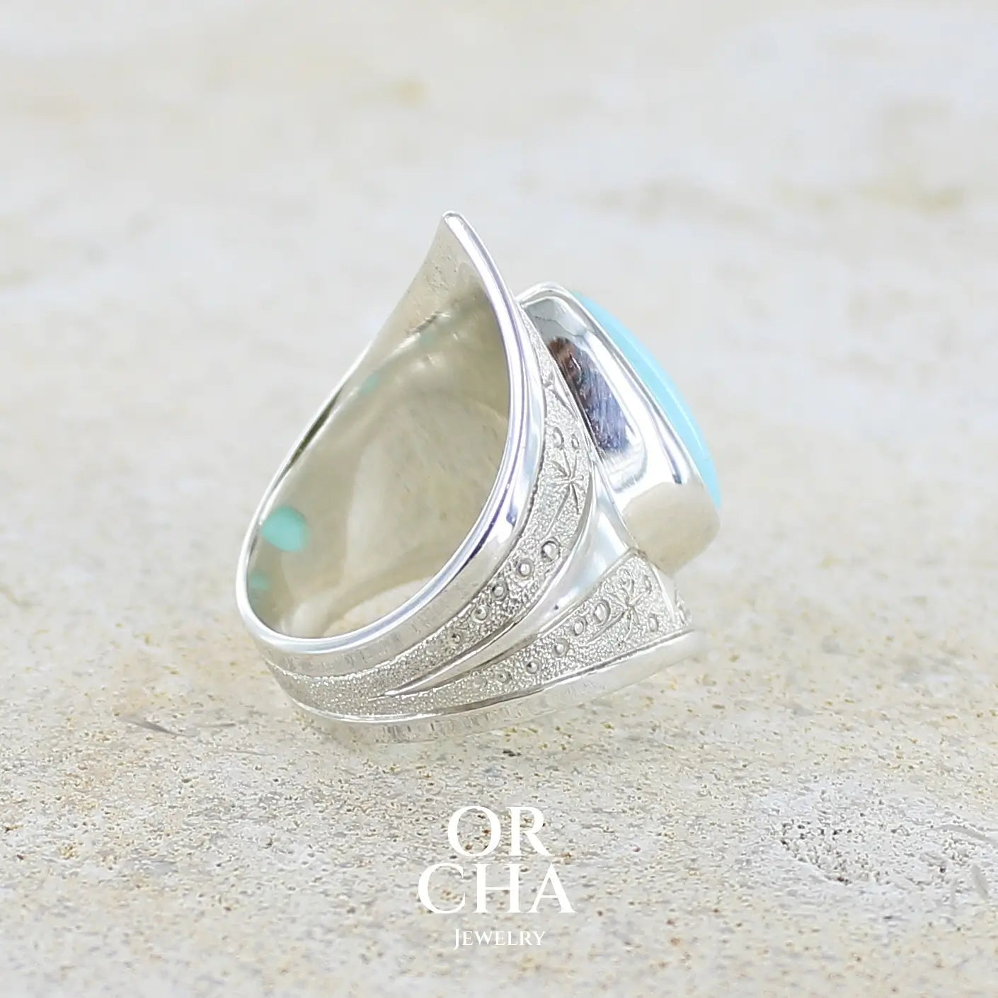 détail du sertissage d'une grande Bague pour femme en argent massif, sertie d'un cabochon d'opale bleue du Pérou de couleur bleu ciel turquoise. Pierre taillée en forme de goutte. de qualité opaque. bijou unique réalisé en taille 52.