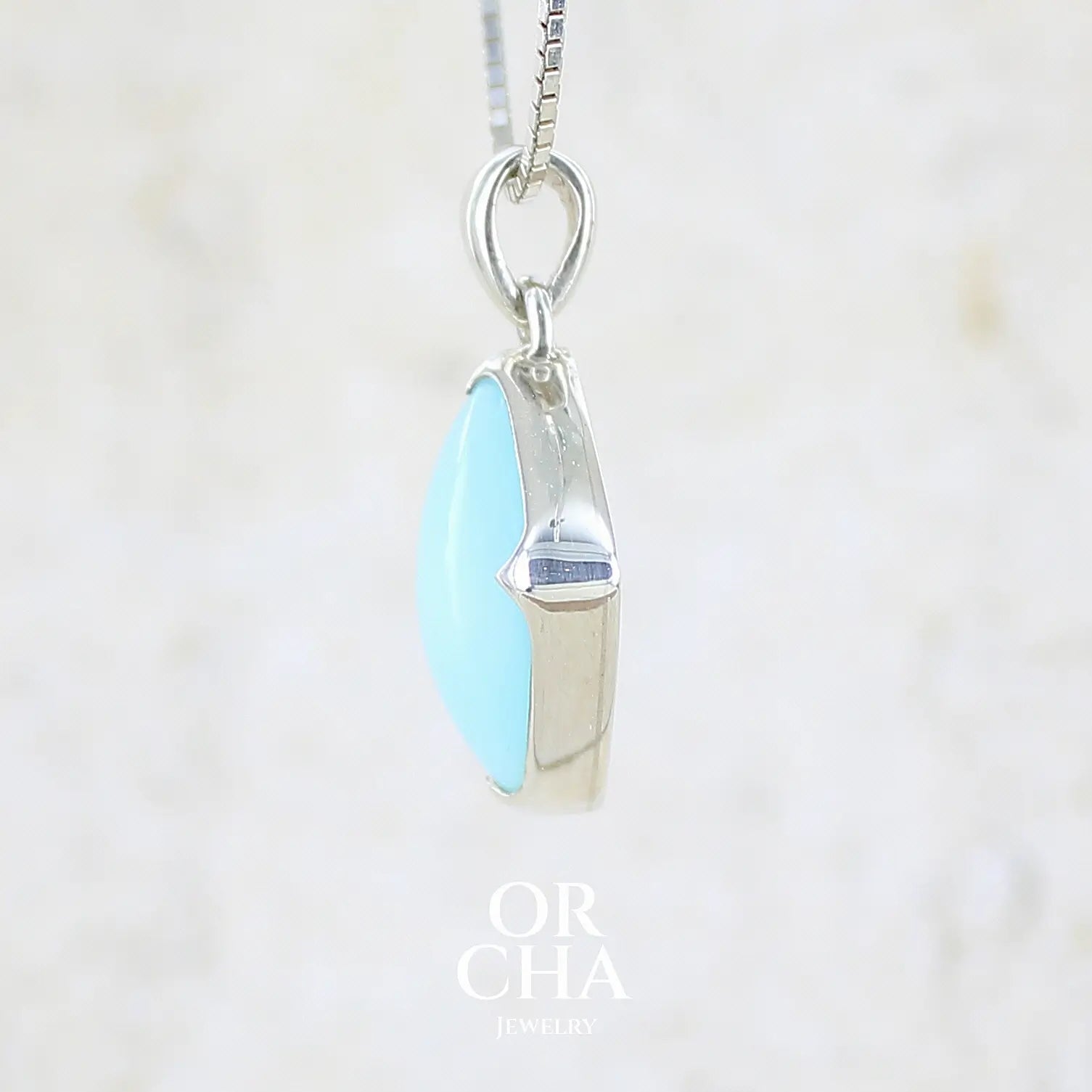 detail sertissage d'un pendentif en argent massif, sertie d'un cabochon d'opale bleue du Pérou de couleur bleu ciel clair. Pierre de forme carrée. Pierre opaque. Bijoux unique, éthique et durable présenté dans un coffret de notre marque, prêt à offrir. Livraison offerte, certificat d'authenticité, service client.