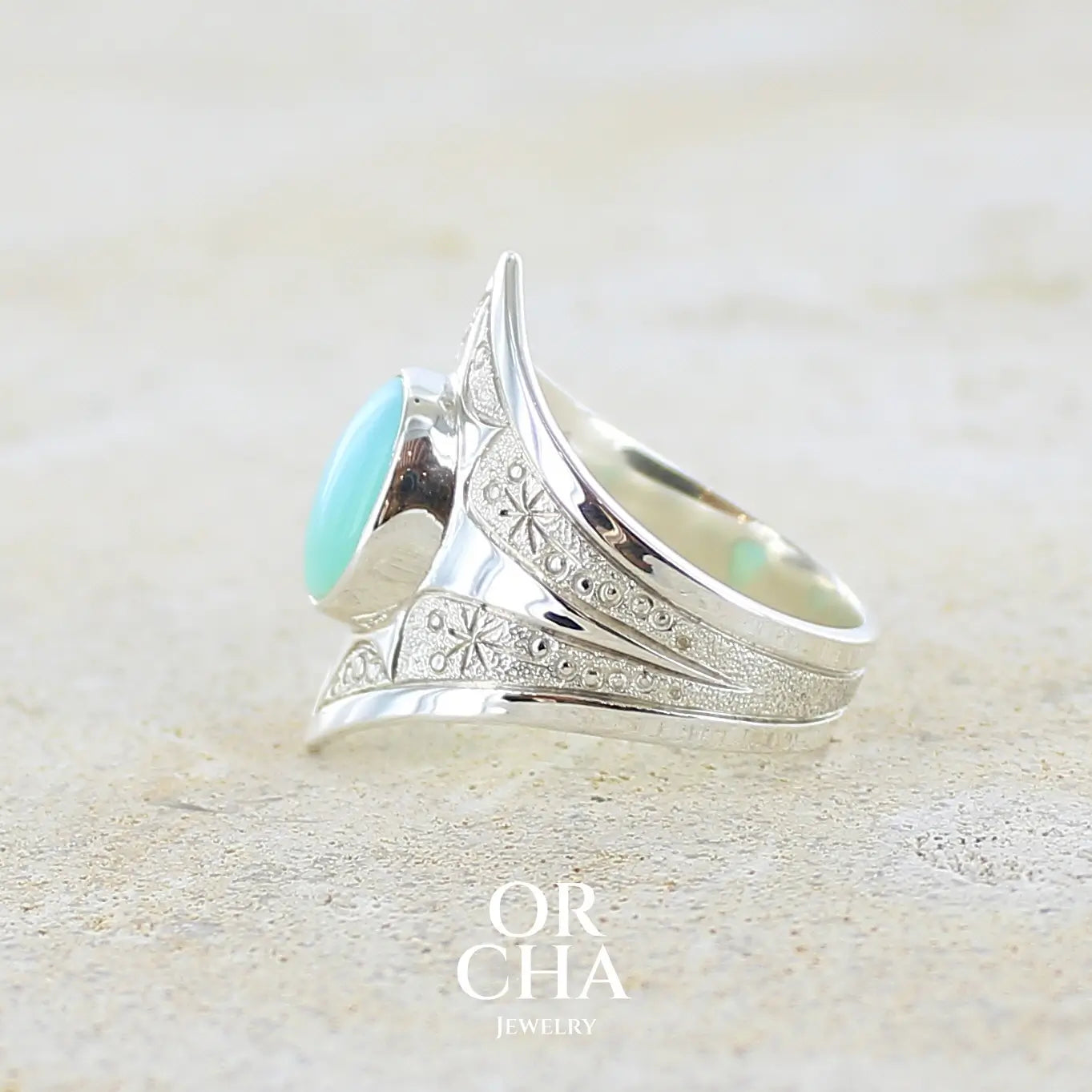 Détail texture d'une bague pour femme en argent massif, sertie d'un cabochon d'opale bleue du Pérou de couleur bleu ciel turquoise. Pierre taillée de forme ovale de qualité opaque. Bijou unique réalisé en taille 60,5.