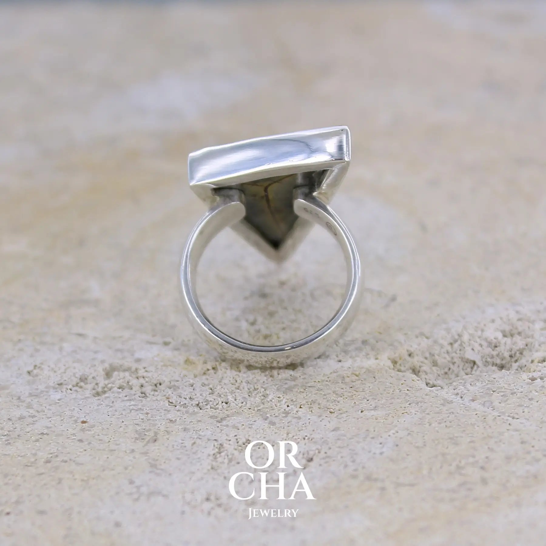 vue de dos d'une grande bague contemporaine pour femme en argent massif sertie d'une tranche de septaria Pierre unique et rare sous cette forme triangulaire. Pierre de qualité opaque naturelle de couleur brun foncé à brun clair. Bague réalisée en taille 54. Bijoux unique, éthique et durable présenté dans un coffret de notre marque, prêt à offrir. Livraison offerte, certificat d'authenticité, service client.
