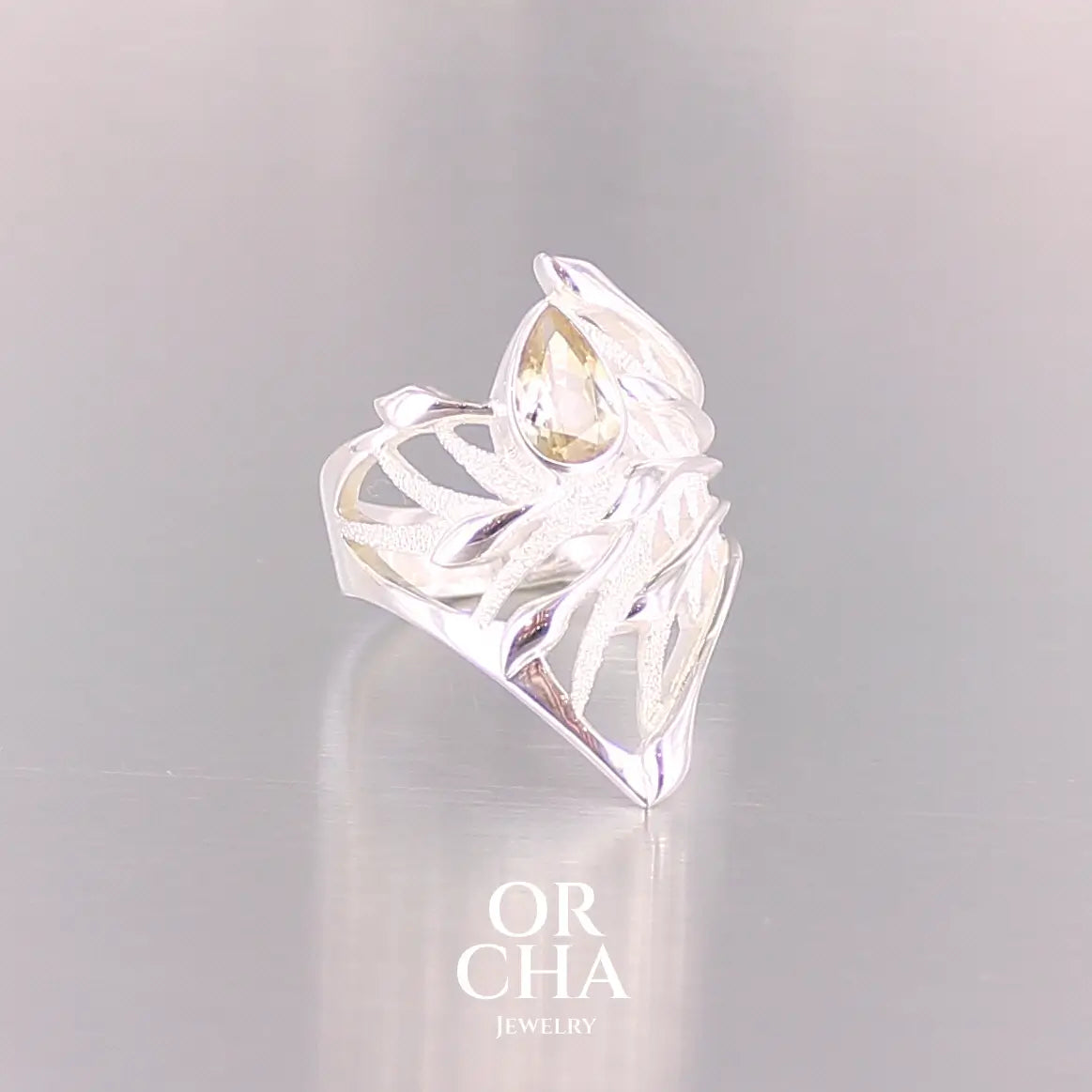 Pofil d'une grande Bague topaze impériale et argent massif illustrant un feuillage tropicale. Bijou pour femme sertie d'une Topaze impériale de couleur jaune pâle doré, pierre  facettée en forme de poire. Pierre très lumineuse et propre à l'oeil. Bijoux unique, éthique et durable présenté dans un coffret de notre marque, prêt à offrir. Livraison offerte, certificat d'authenticité, service client.