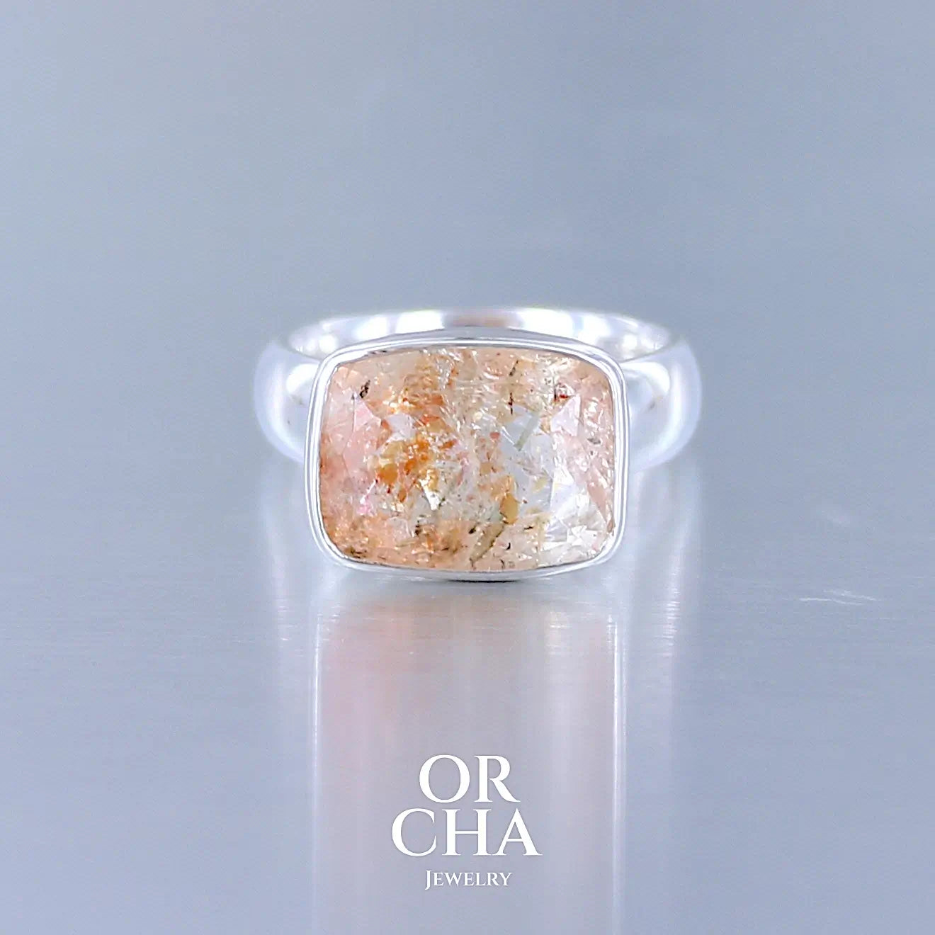 Bague cocktail pour femme en argent massif sertie d'une pierre de soleil oranges de très belle qualité, pierre transparente avec inclusions scintillantes d'hématites.Pierre naturelle facettée de forme rectangulaire. Tailles 54. Bijoux unique, éthique et durable présenté dans un coffret de notre marque, prêt à offrir. Livraison offerte, certificat d'authenticité, service client.
