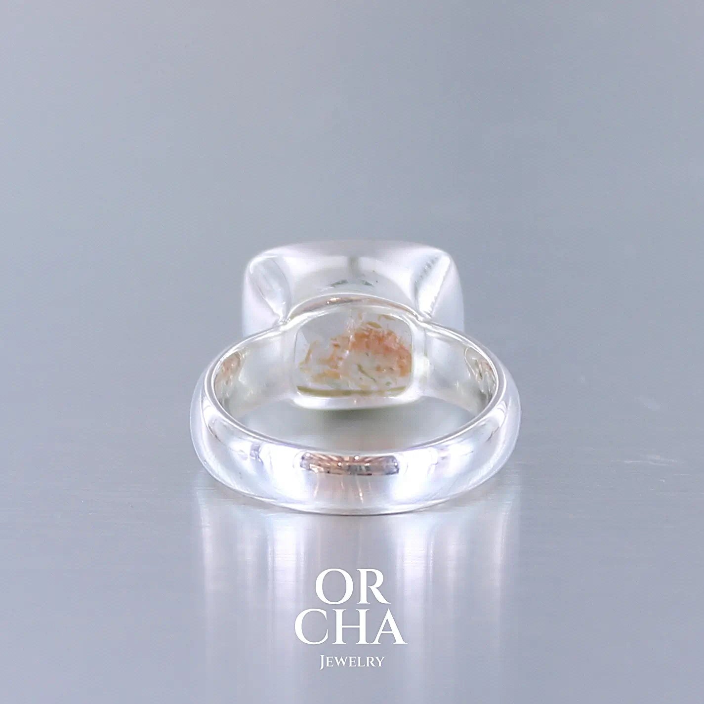 Vue arrière d'une bague cocktail pour femme en argent massif sertie d'une pierre de soleil oranges de très belle qualité, pierre transparente avec inclusions scintillantes d'hématites.Pierre naturelle facettée de forme rectangulaire. Tailles 54. Bijoux unique, éthique et durable présenté dans un coffret de notre marque, prêt à offrir. Livraison offerte, certificat d'authenticité, service client.