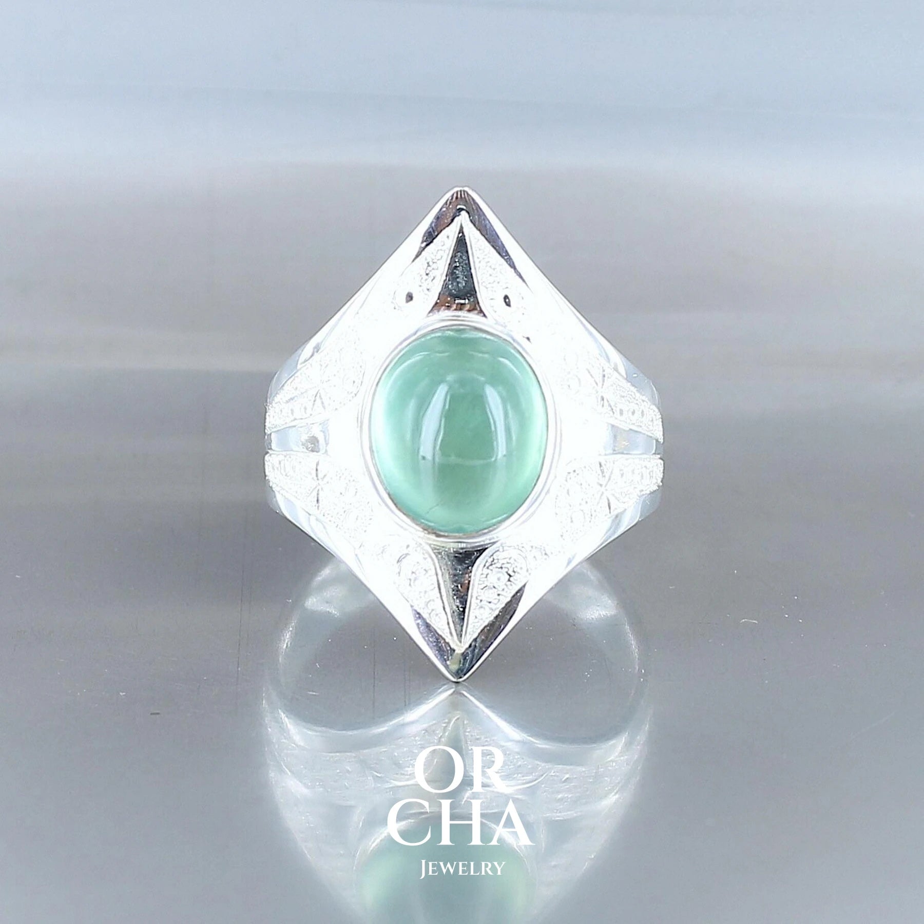 longue bague en argent massif sculptée d'étoiles et autres corps célestes. La bague est sertie d'un cabochon oval de Préhnite de couleur vert bleuté de belle qualité. Bague réalisée en taille 57.